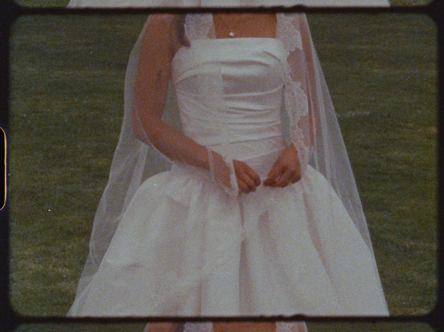 Close-up detail of bride in elegant strapless white satin wedding gown with delicate lace veil.