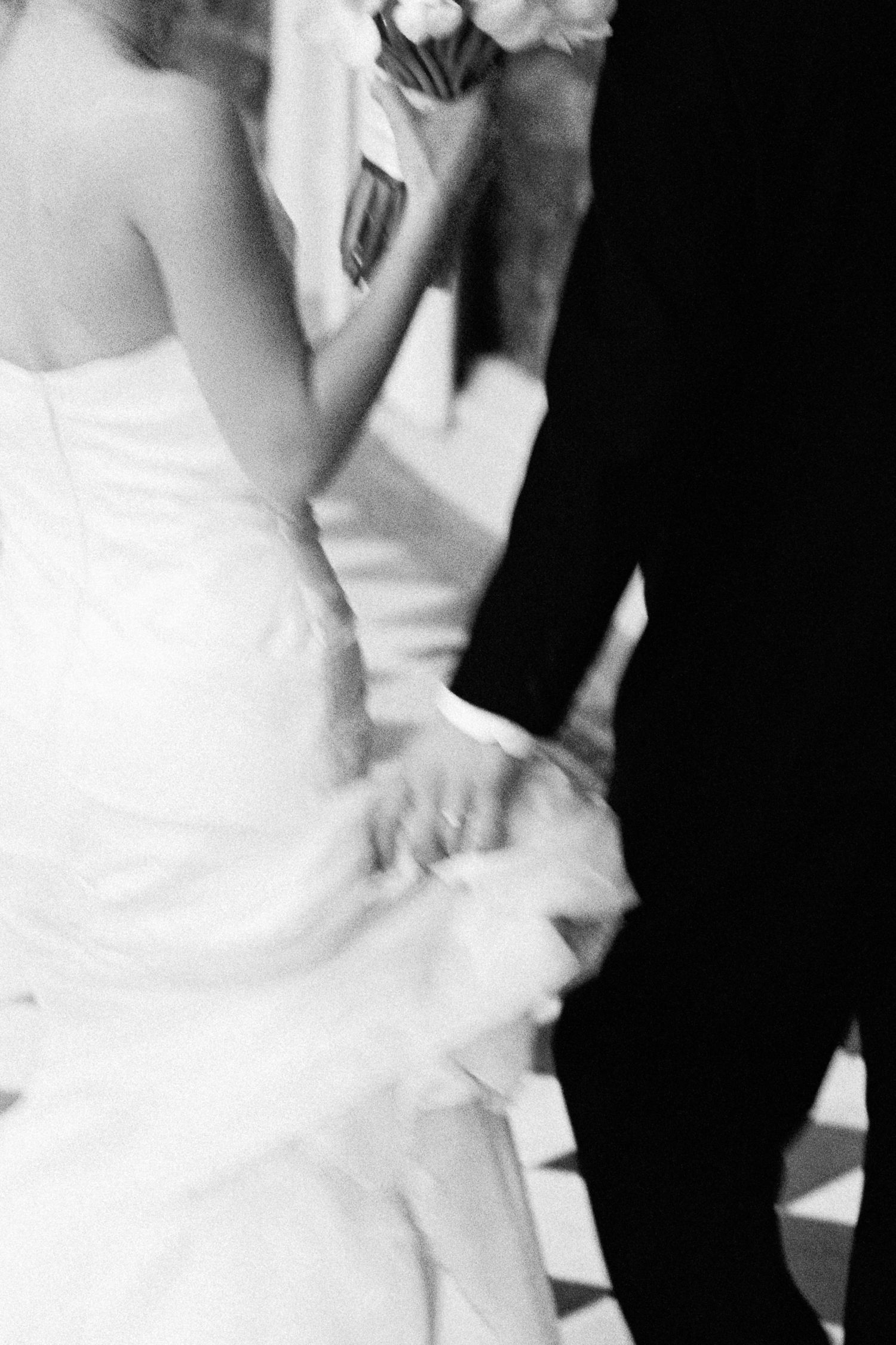Close-up of bride and groom holding hands during outdoor wedding ceremony.