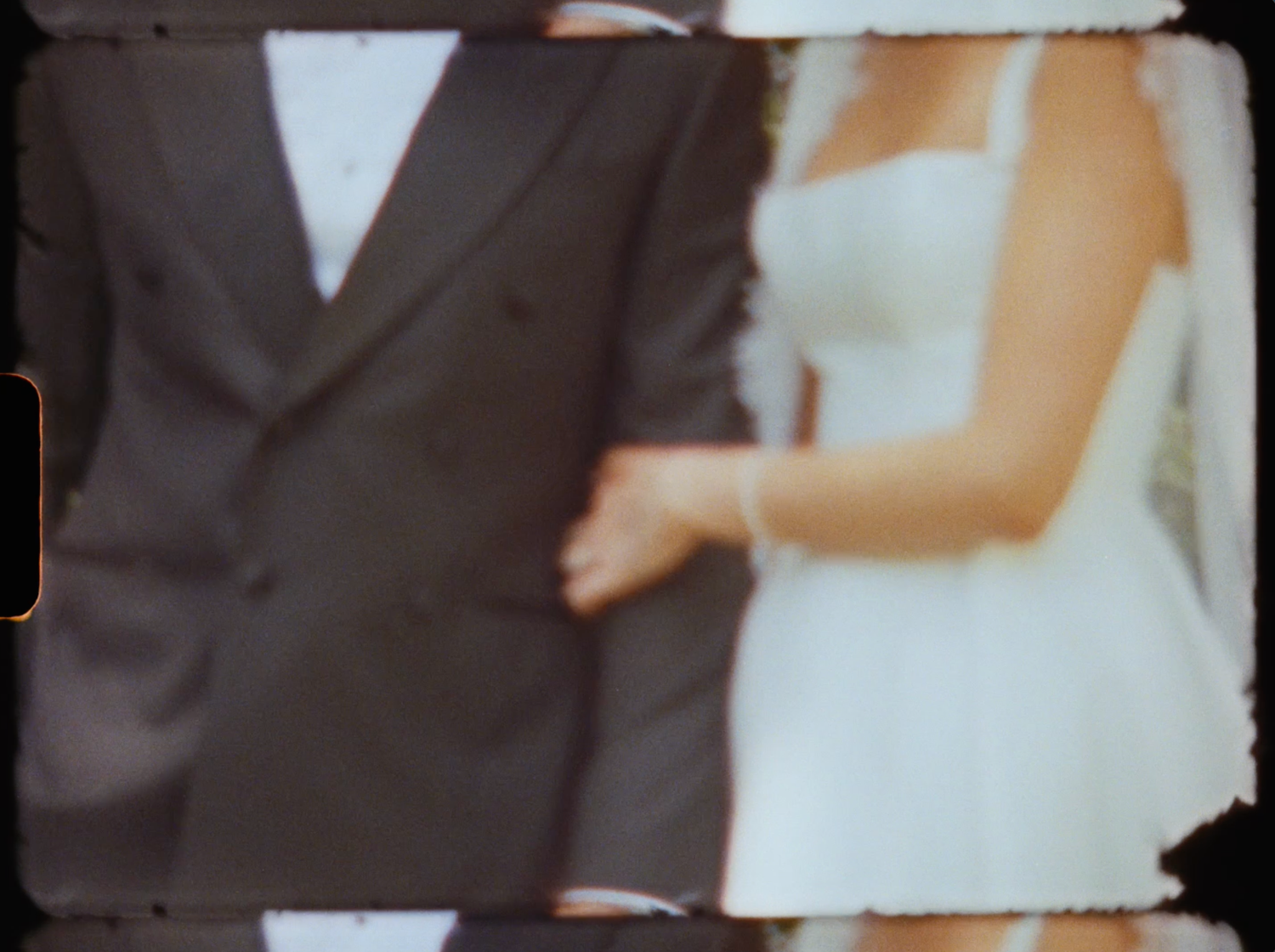 Close-up of a bride in a white dress and groom in a dark suit holding hands at their wedding.
