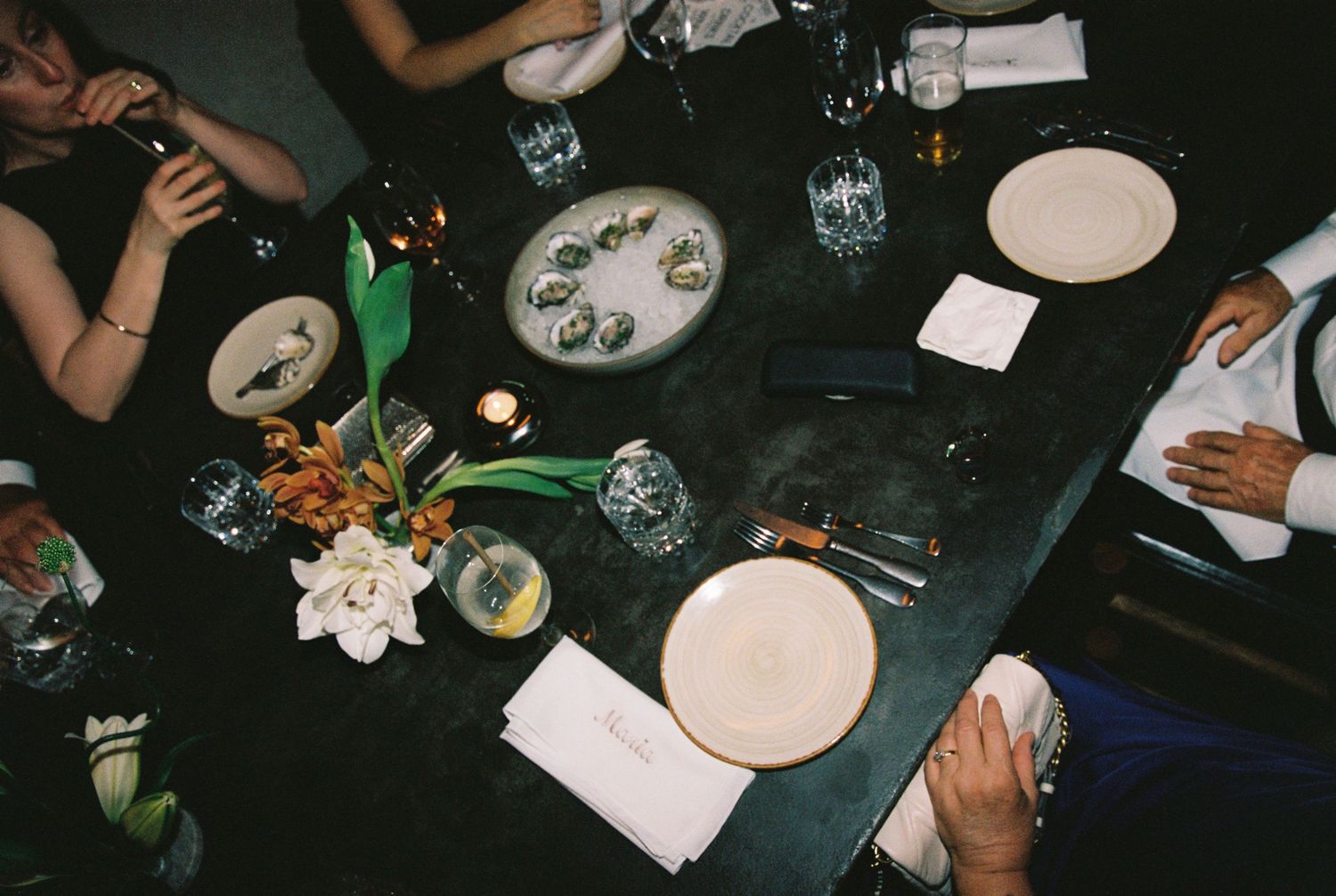 Elegant wedding reception table with oysters, floral centerpiece, candles, and place settings.