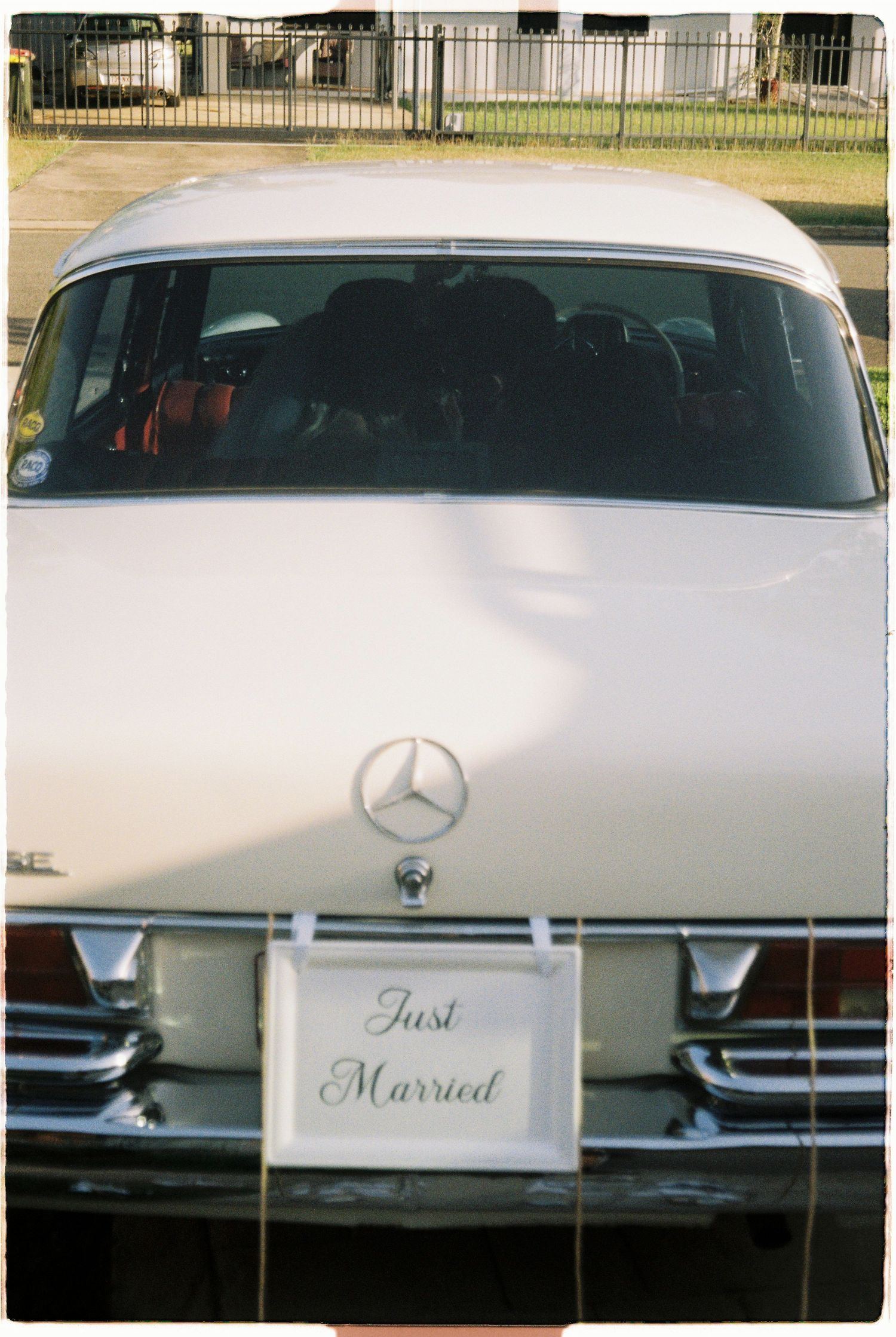 Vintage white Mercedes-Benz wedding car with a Just Married license plate sign attached.
