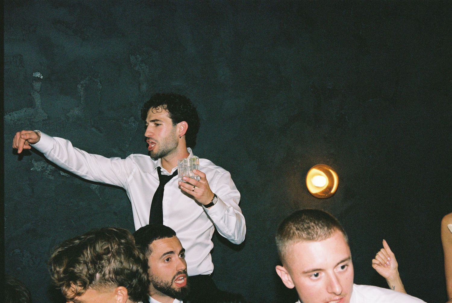 Young man dancing energetically at a wedding reception under warm ambient lighting.