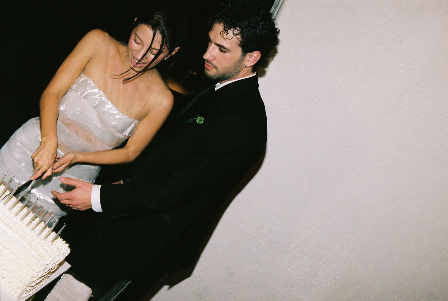Bride and groom cutting white wedding cake together at their reception.