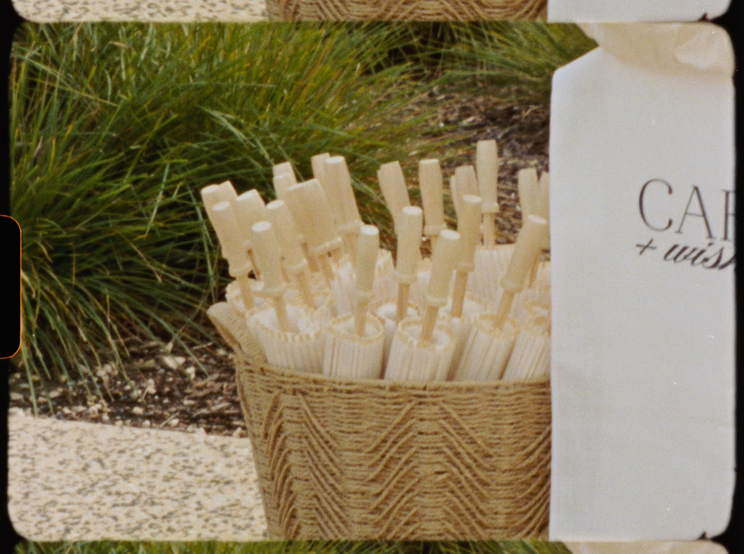 Wicker basket filled with white wish sticks for a wedding card and wishes station outdoors.