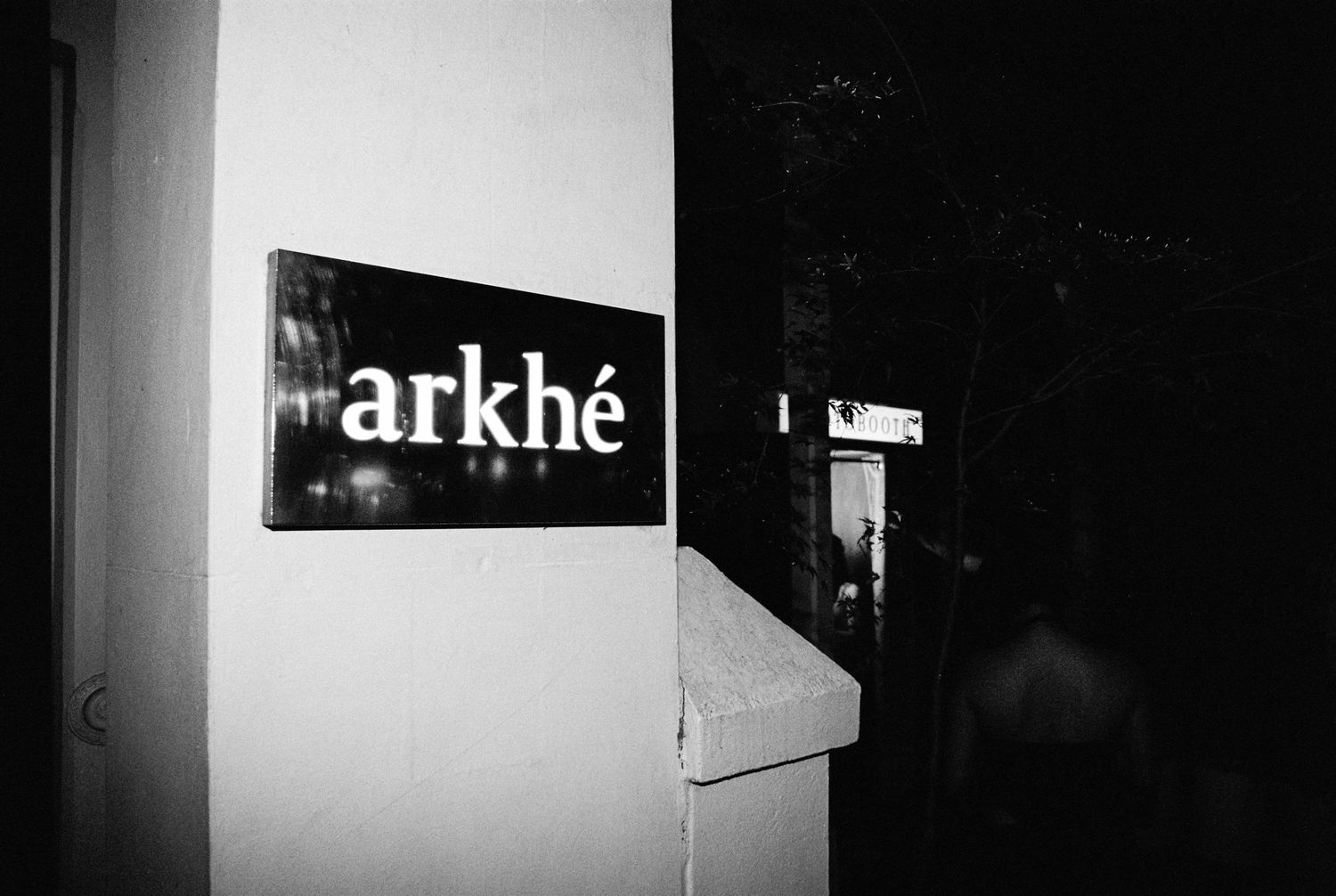 Black and white sign reading Arkhe mounted on wall at wedding venue entrance.