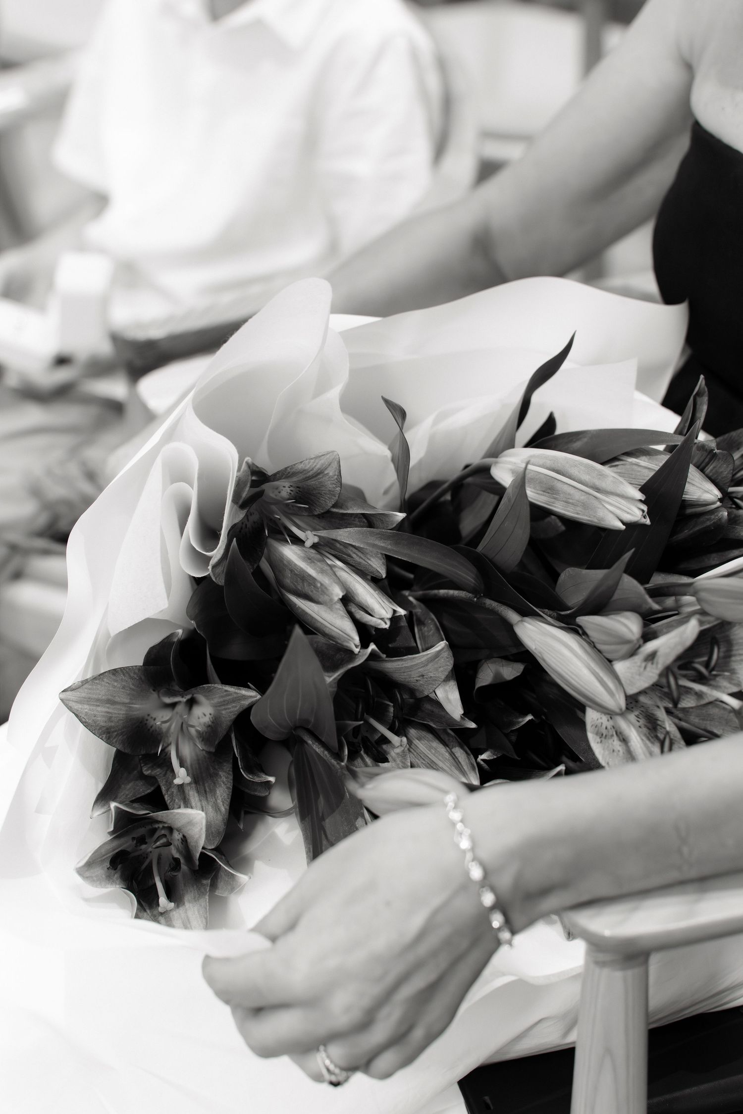 Close-up black and white photo of a bouquet of lilies held during a wedding ceremony.