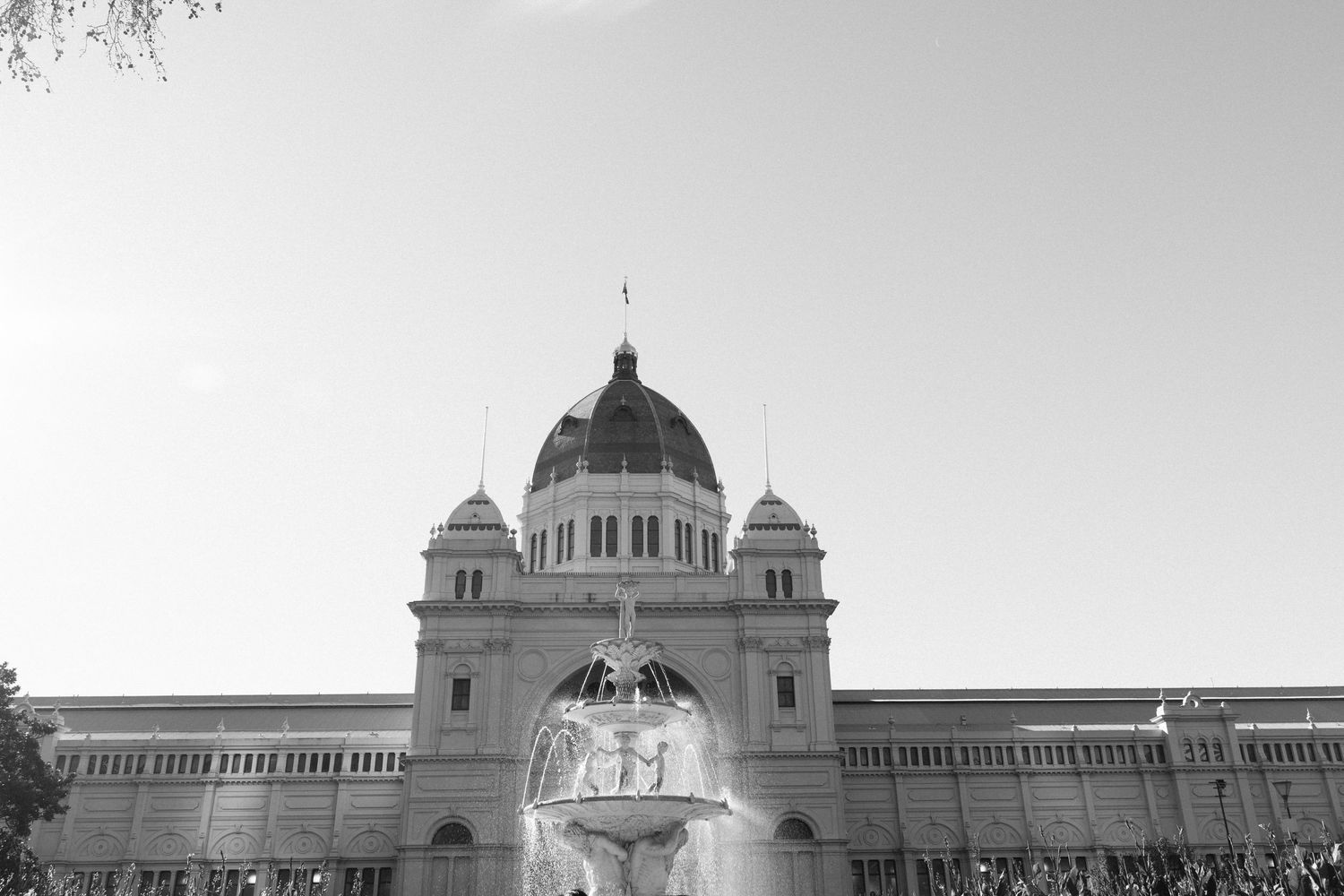 Black and white photo of the Royal Exhibition Building in Melbourne with a fountain in the foreground.