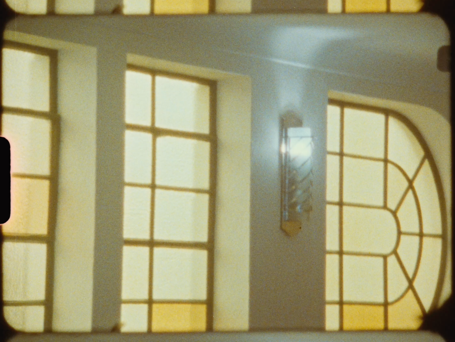 Elegant interior with large arched windows casting warm golden light on white walls in vintage film style.
