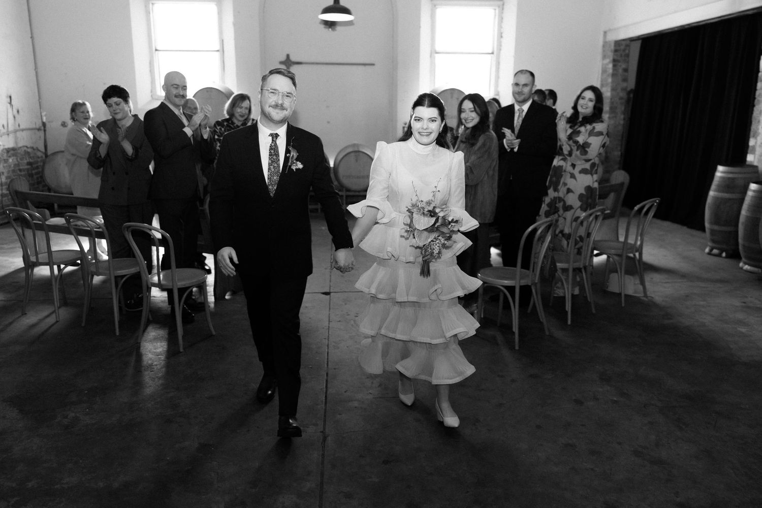 Black and white photo of a bride and groom walking down the aisle at their wedding ceremony.