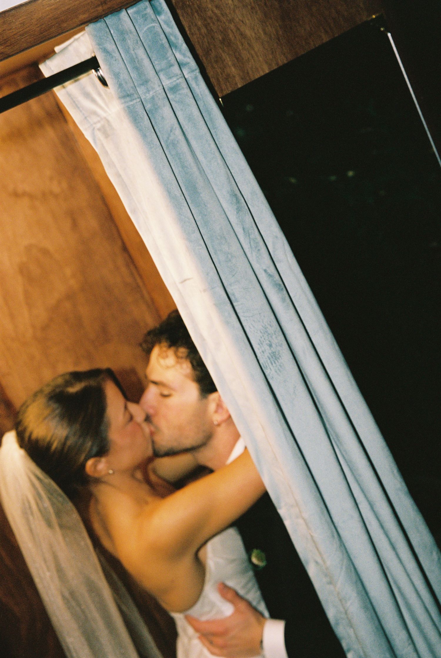 Bride and groom share a romantic kiss inside a photo booth at their wedding reception.
