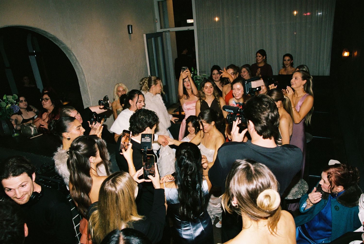 Guests celebrate and take photos at a lively wedding reception party.