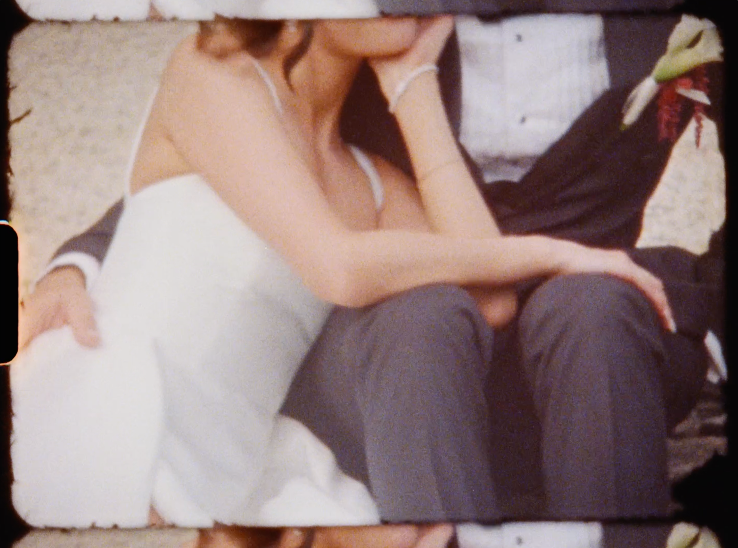 Close-up of bride in white dress and groom in dark suit sitting together at wedding.
