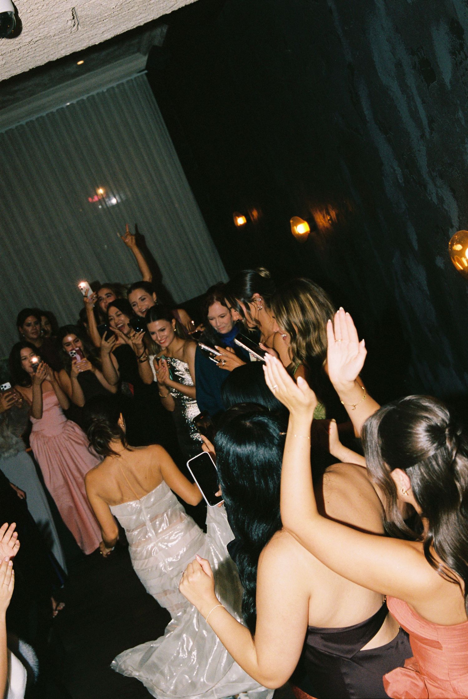 Guests dancing and celebrating on the wedding reception dance floor at night.
