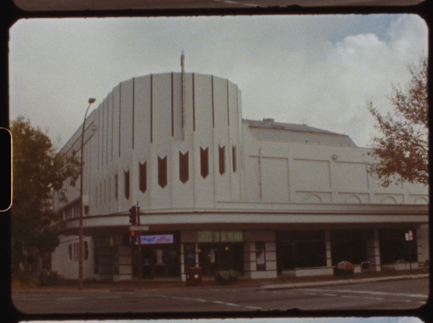 Classic art deco cinema building exterior with curved white facade on a street corner.