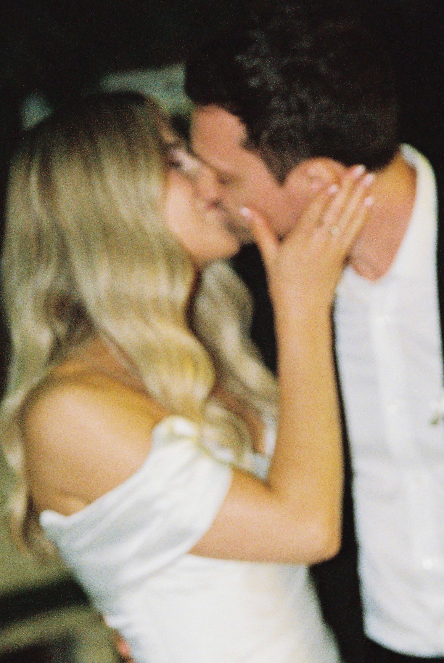 Bride and groom share a close romantic kiss at their wedding celebration.