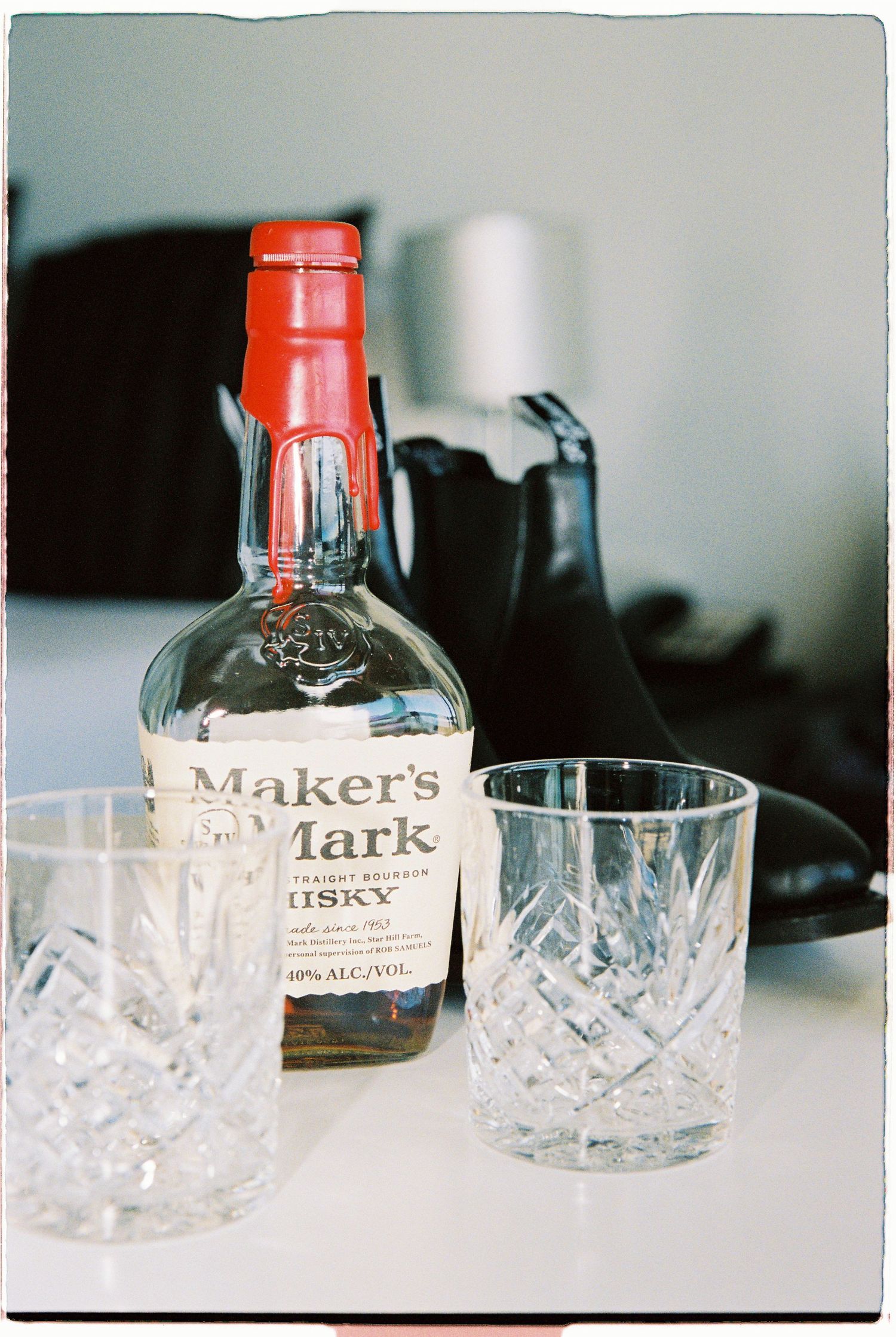 Makers Mark Kentucky straight bourbon whisky bottle with crystal rocks glasses on a white surface.