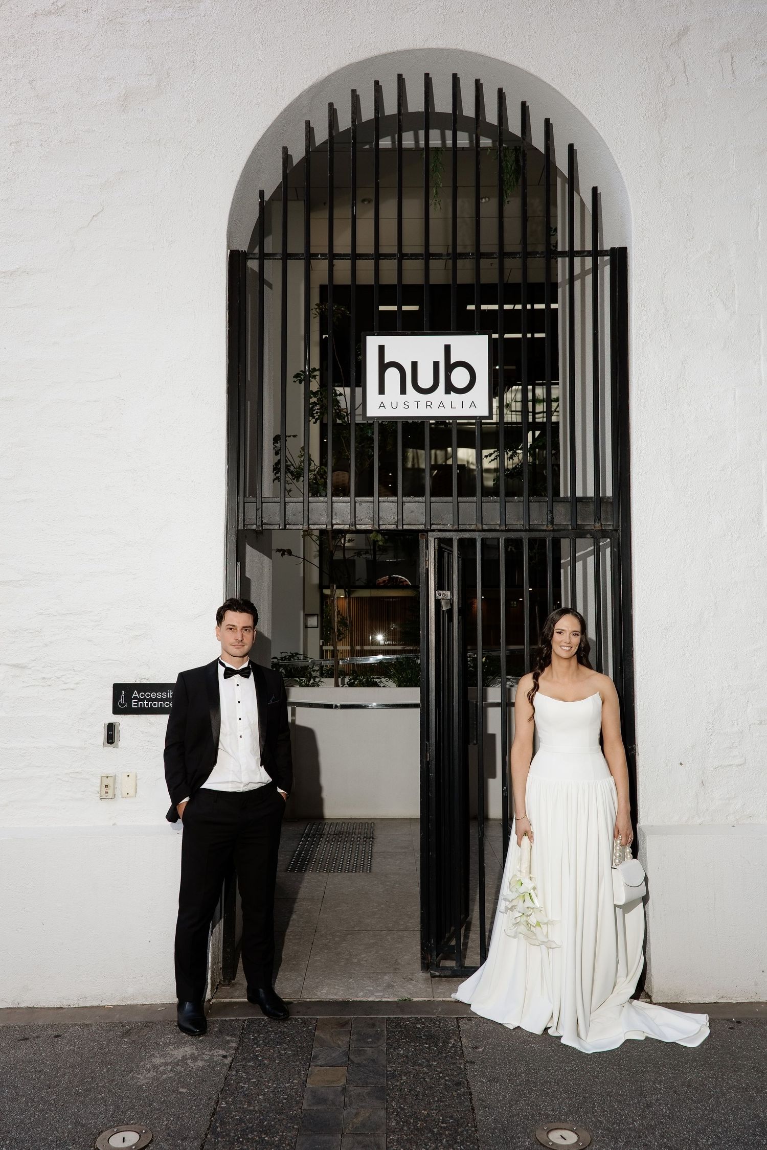 Bride and groom posing at the entrance of Hub Australia under a white arched doorway.