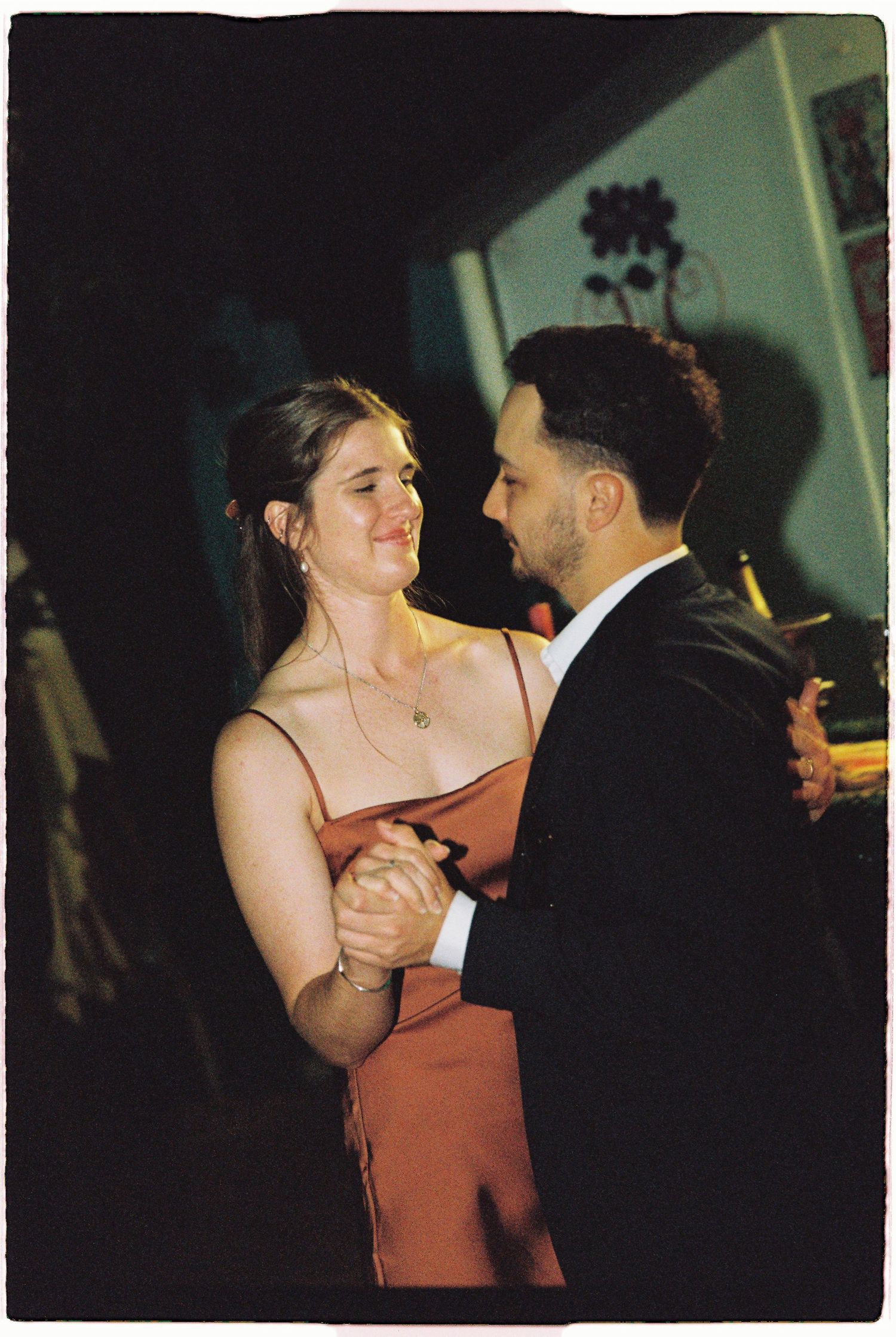 Couple sharing romantic dance in warm evening light at wedding reception.