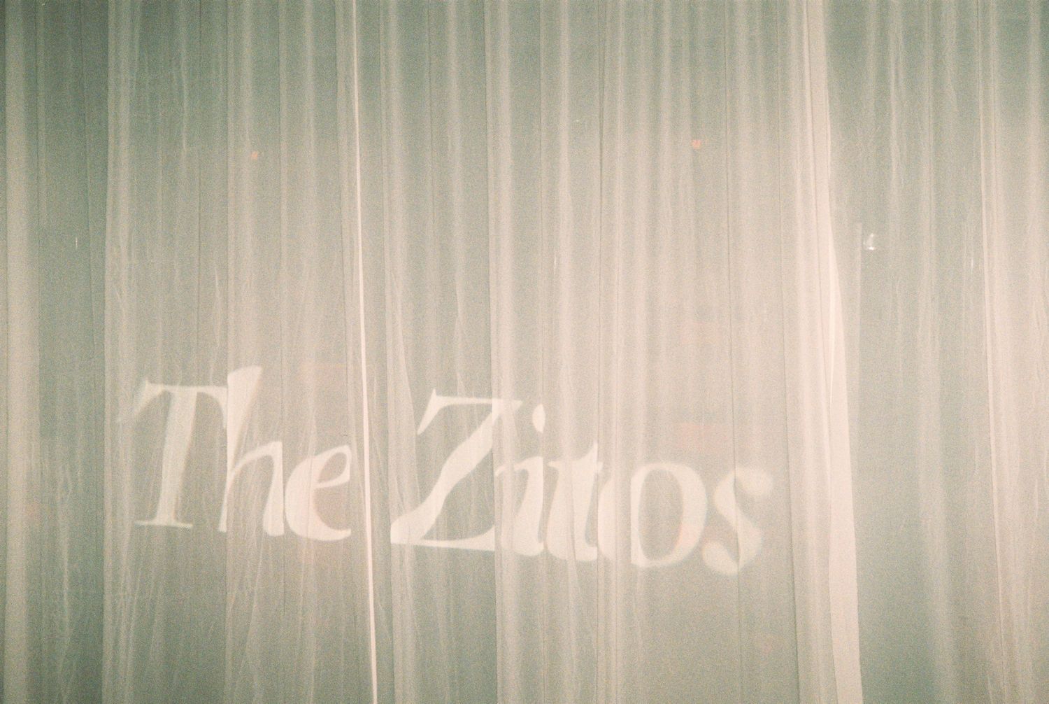 Elegant sheer curtain displaying The Ziitos wedding monogram in soft white lettering.