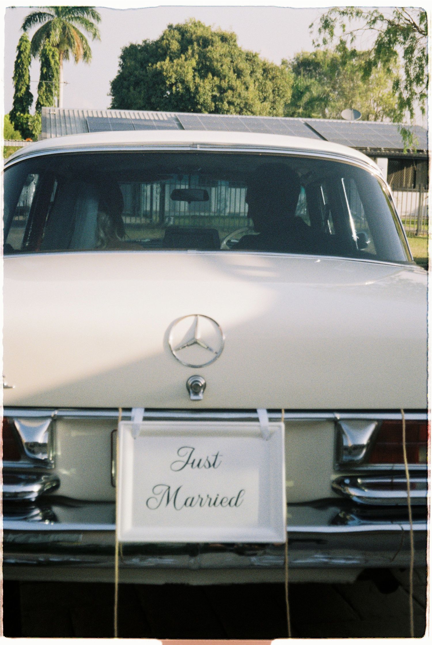 Vintage cream Mercedes-Benz car with Just Married license plate sign at wedding celebration.
