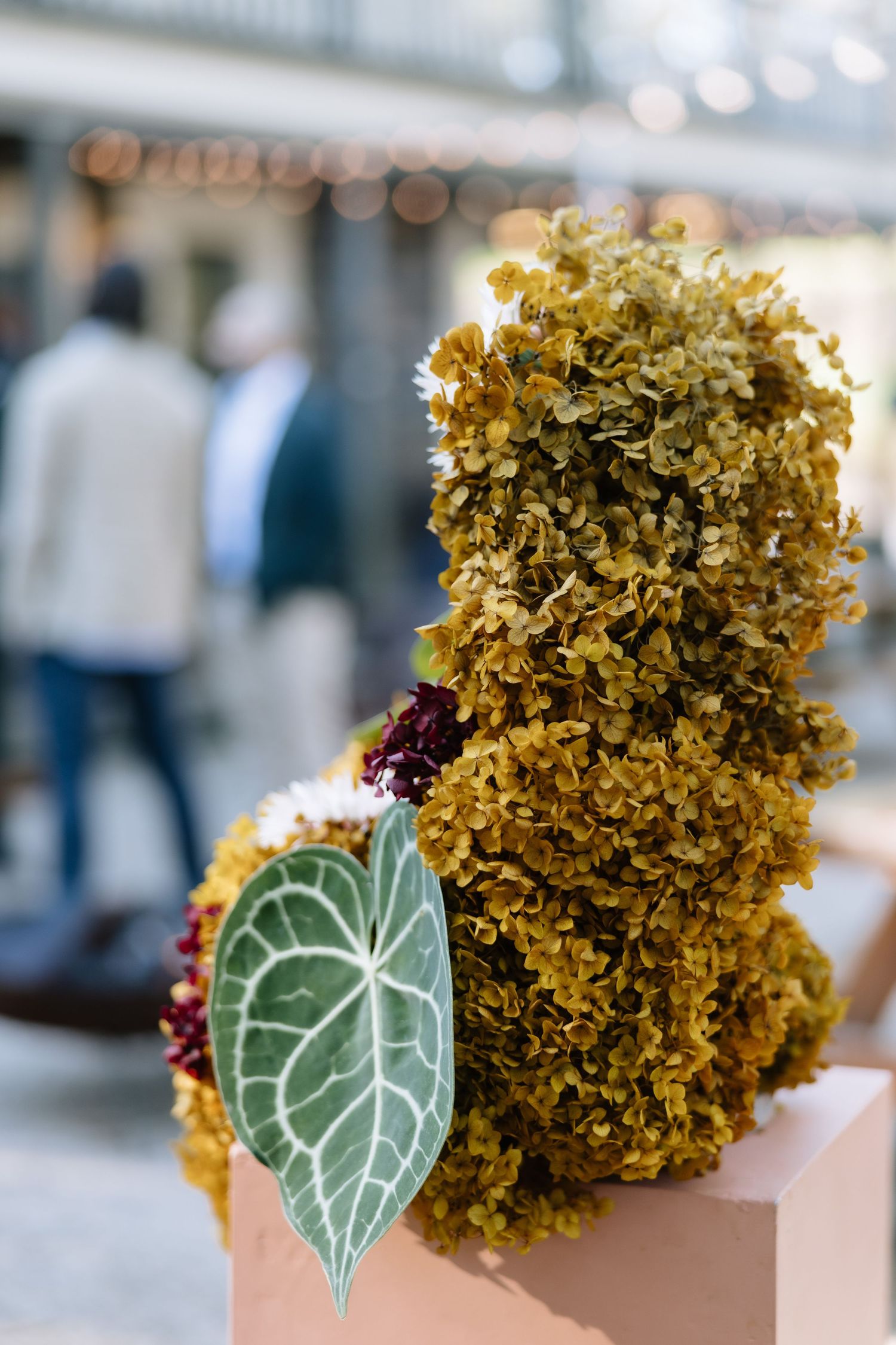 A floral teddy bear sculpture made of green hydrangeas with a decorative leaf accent displayed indoors.