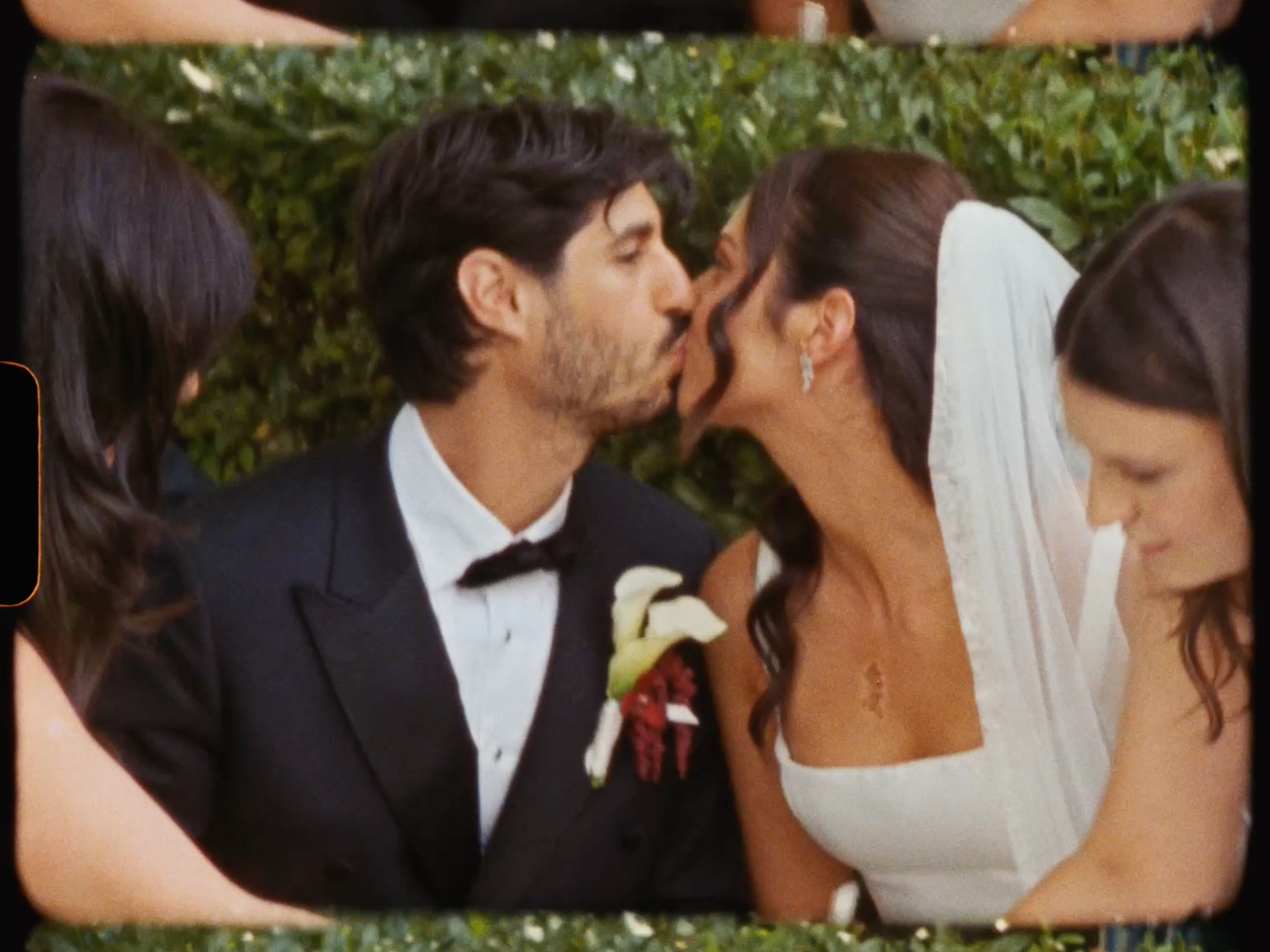 Bride and groom share a tender kiss during their outdoor wedding ceremony surrounded by guests.
