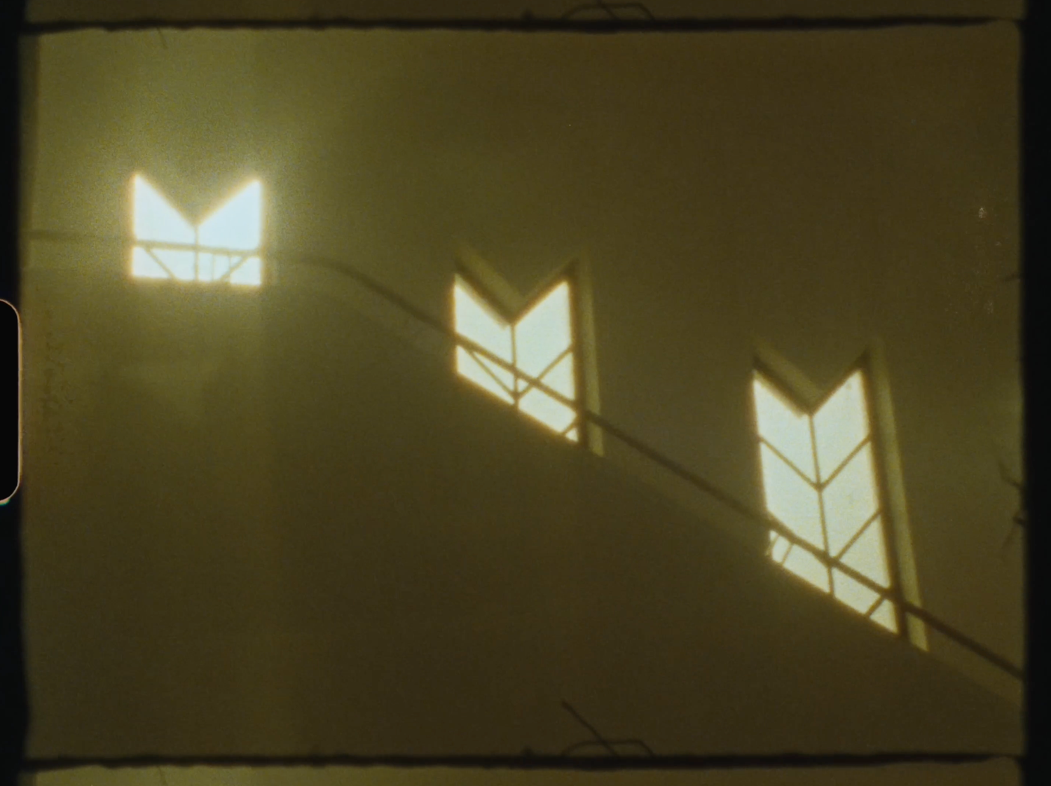 Art deco stained glass windows casting golden arrow-shaped light patterns on a warm amber wall.