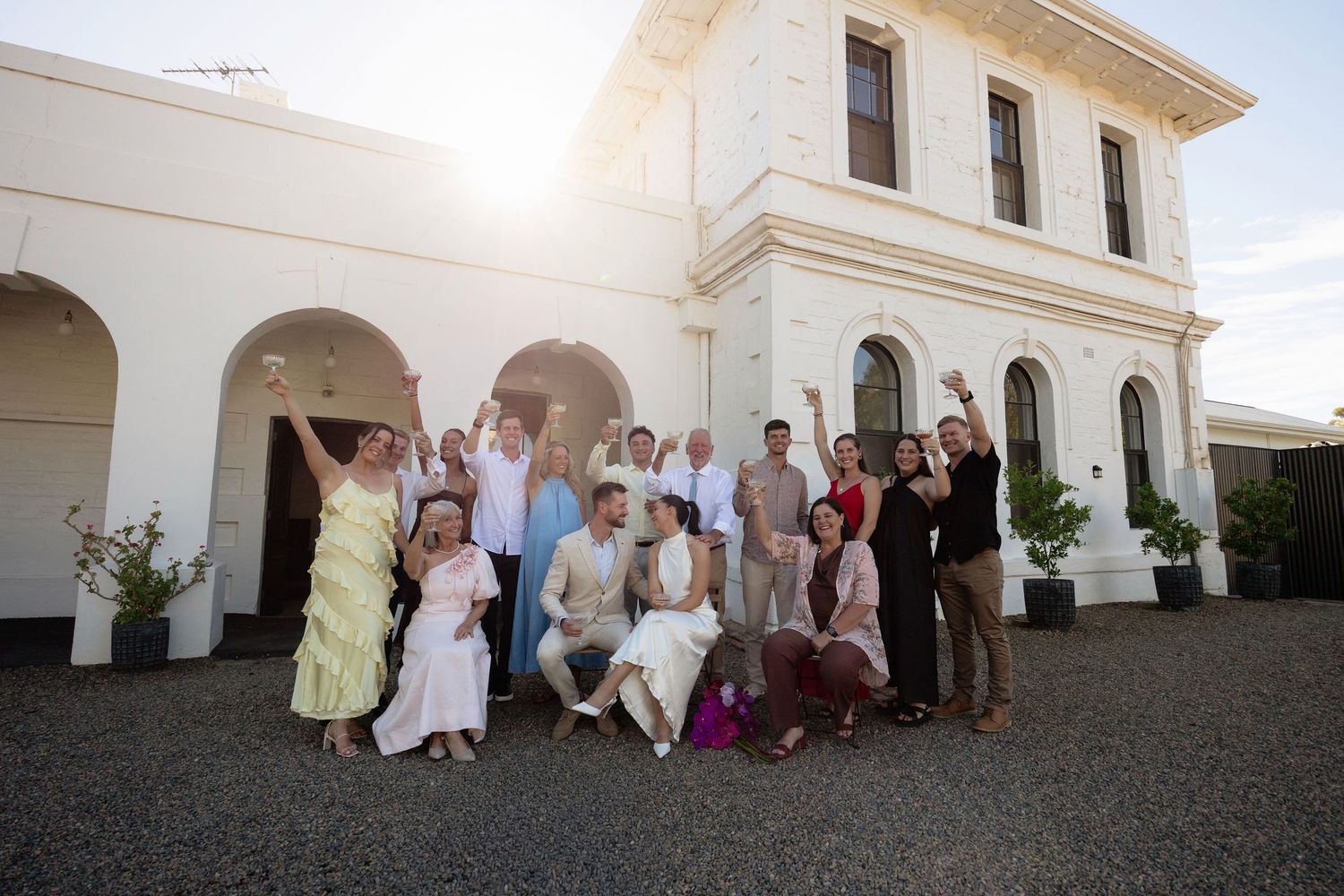 Large wedding party group photo celebrating outside a grand white colonial building.
