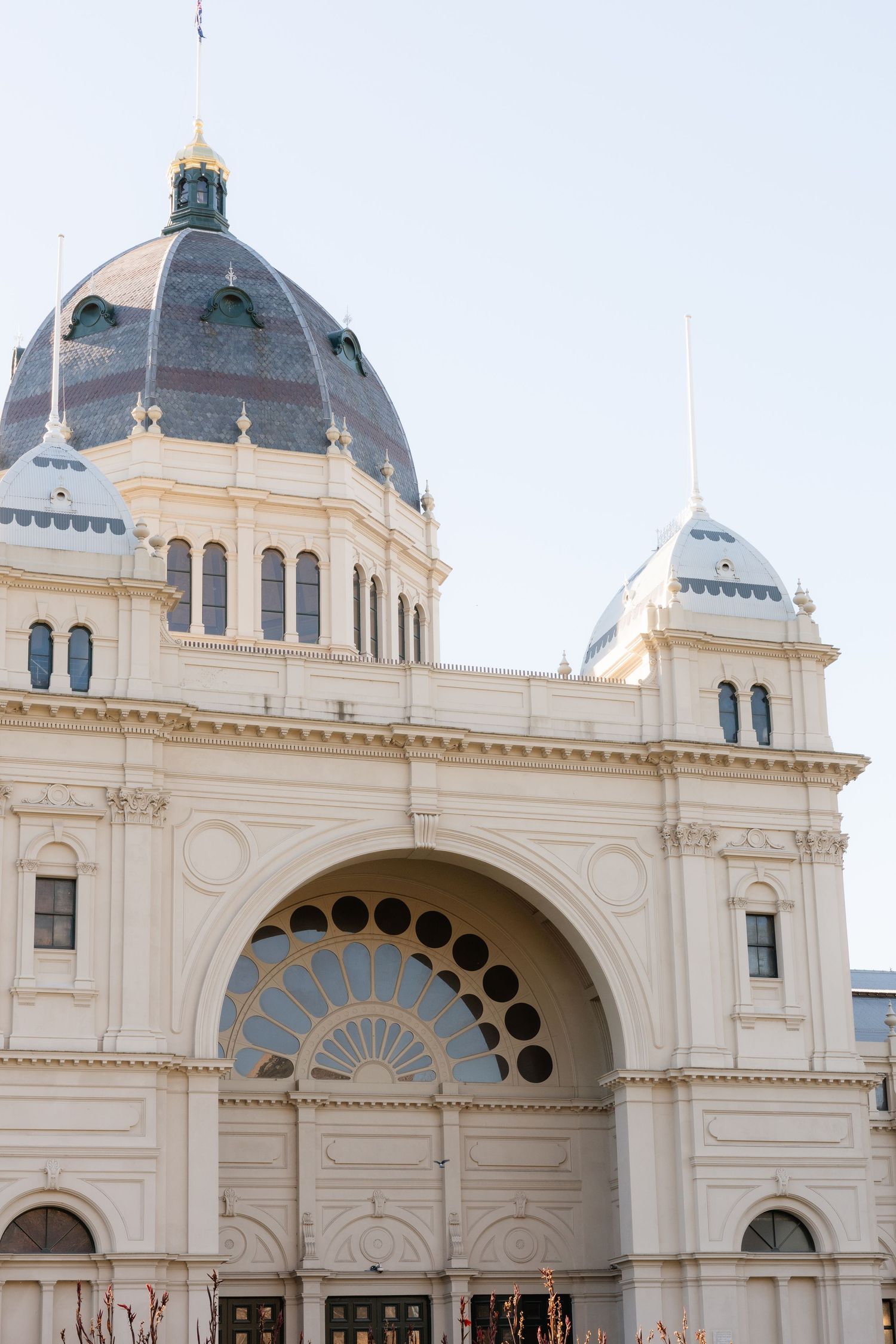 Royal Exhibition Building in Melbourne featuring ornate white facade, large arched entrance, and iconic dome against a clear sky.
