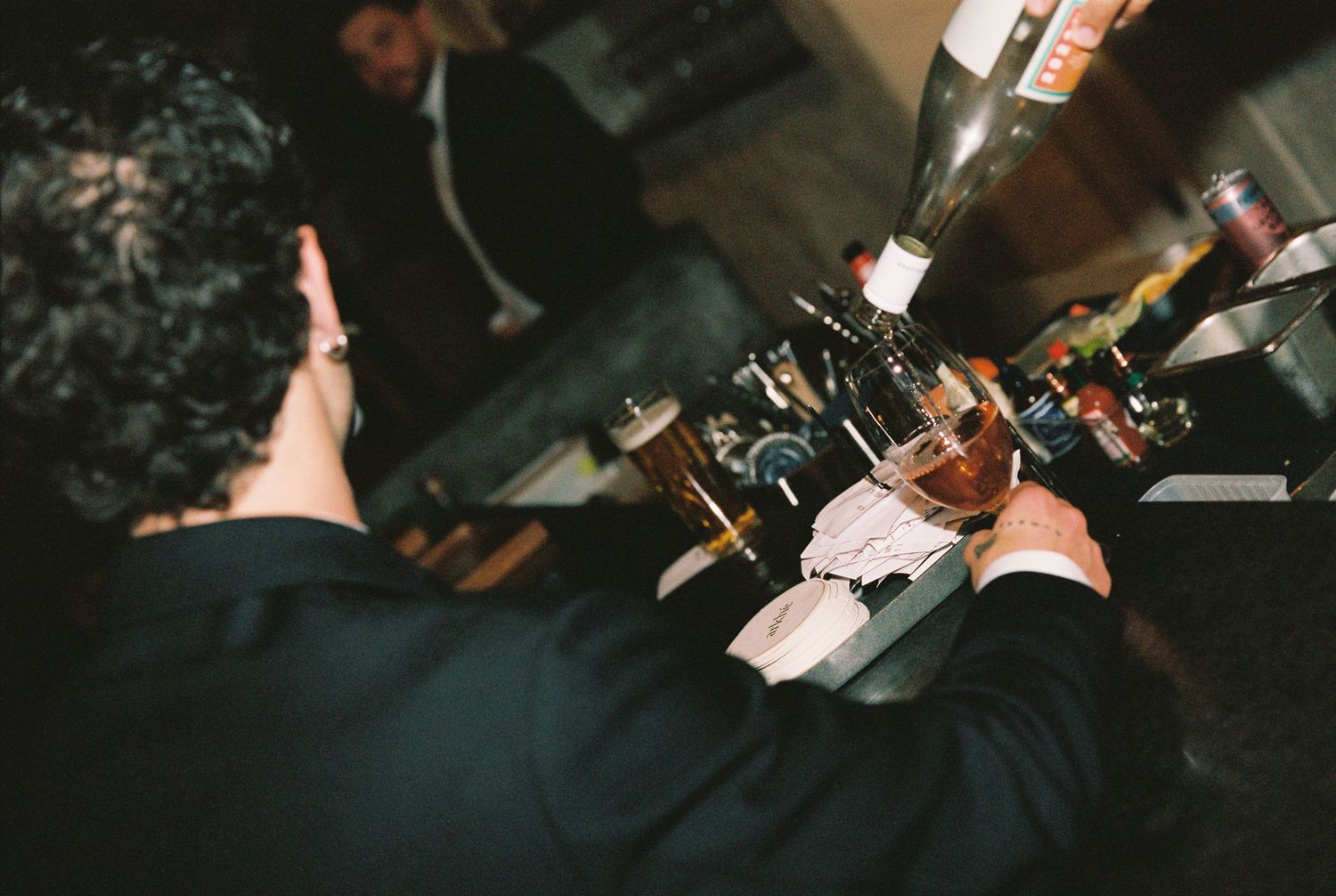 Bartender serving drinks at a dimly lit wedding reception bar.