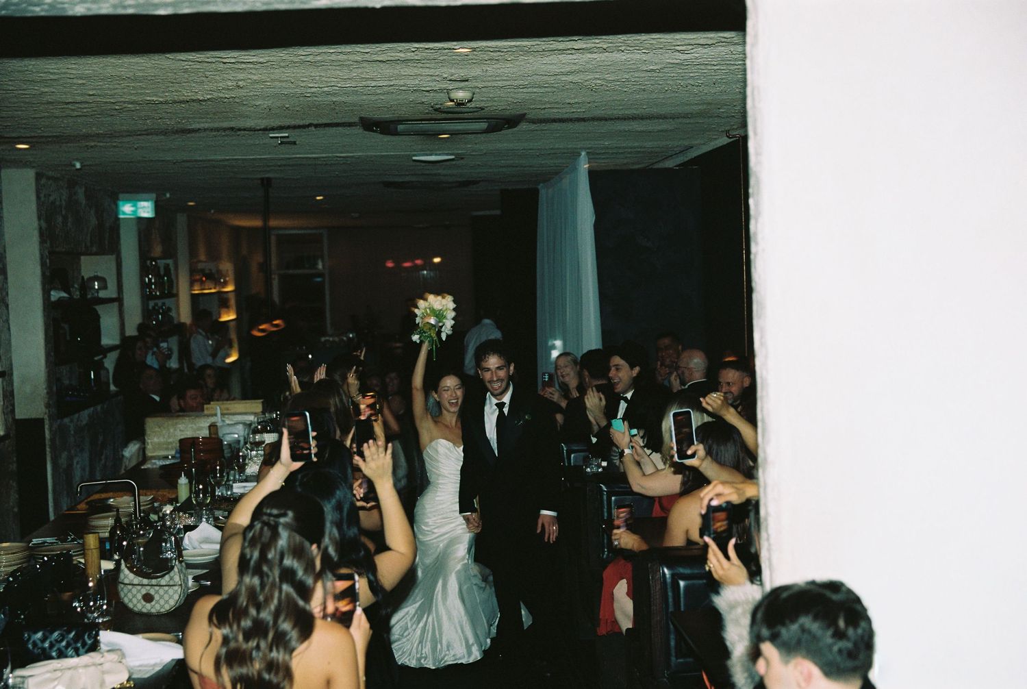 Bride and groom making grand entrance into wedding reception to cheering guests.