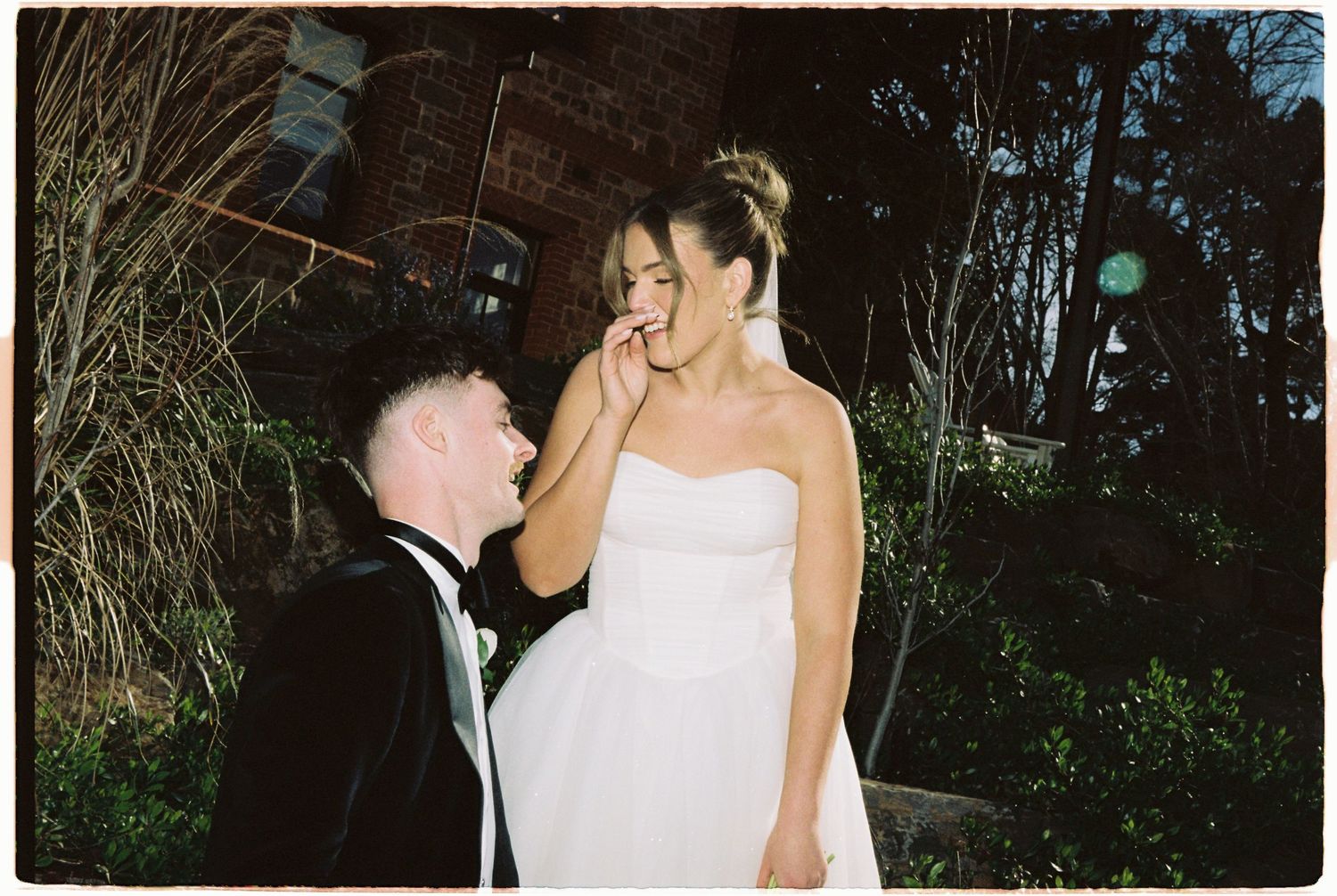 Bride and groom sharing a joyful moment together outside at night during their wedding.