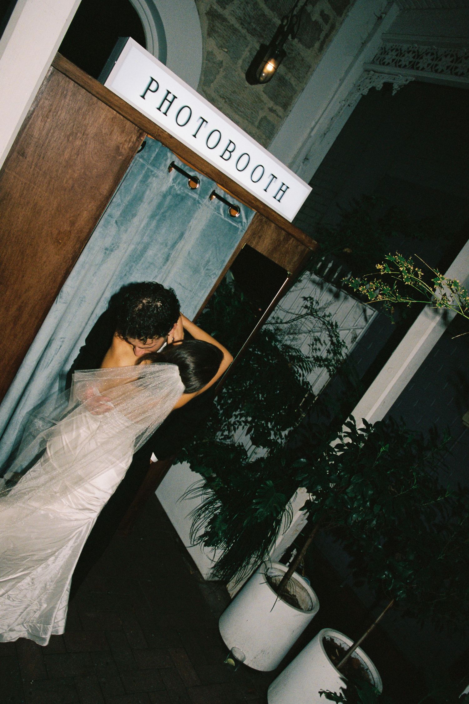 Bride in white wedding gown entering a photobooth at her wedding reception venue.