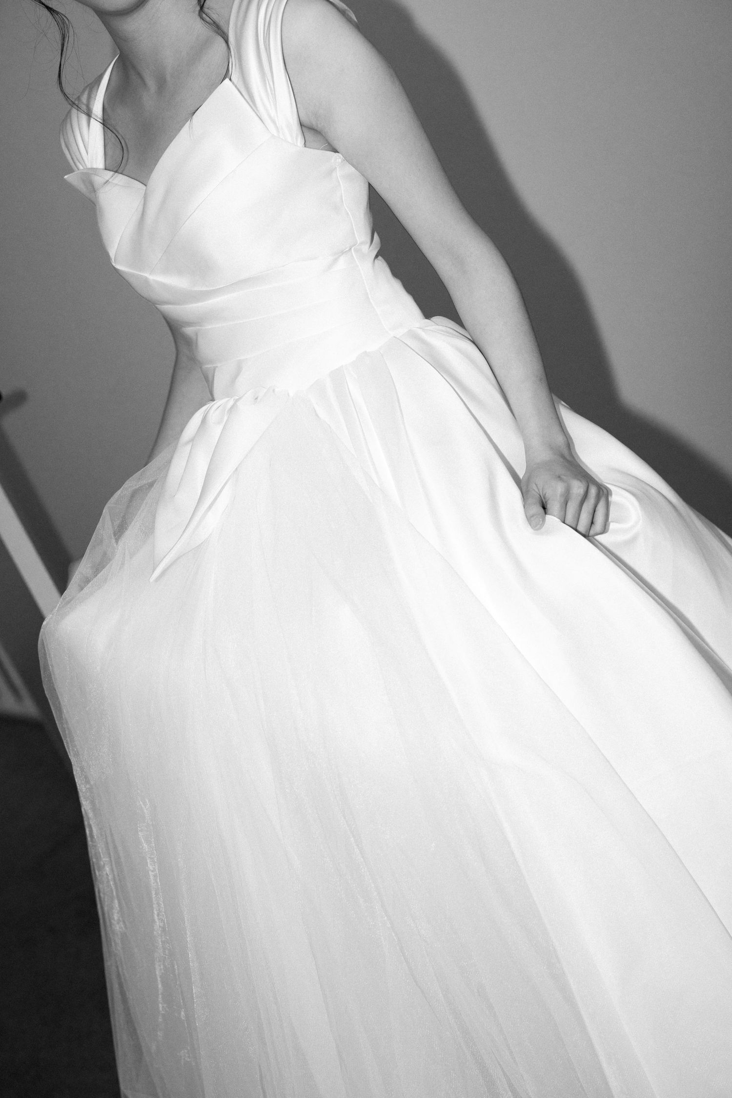Black and white photo of a bride in a flowing white tulle ball gown wedding dress with a fitted bodice.