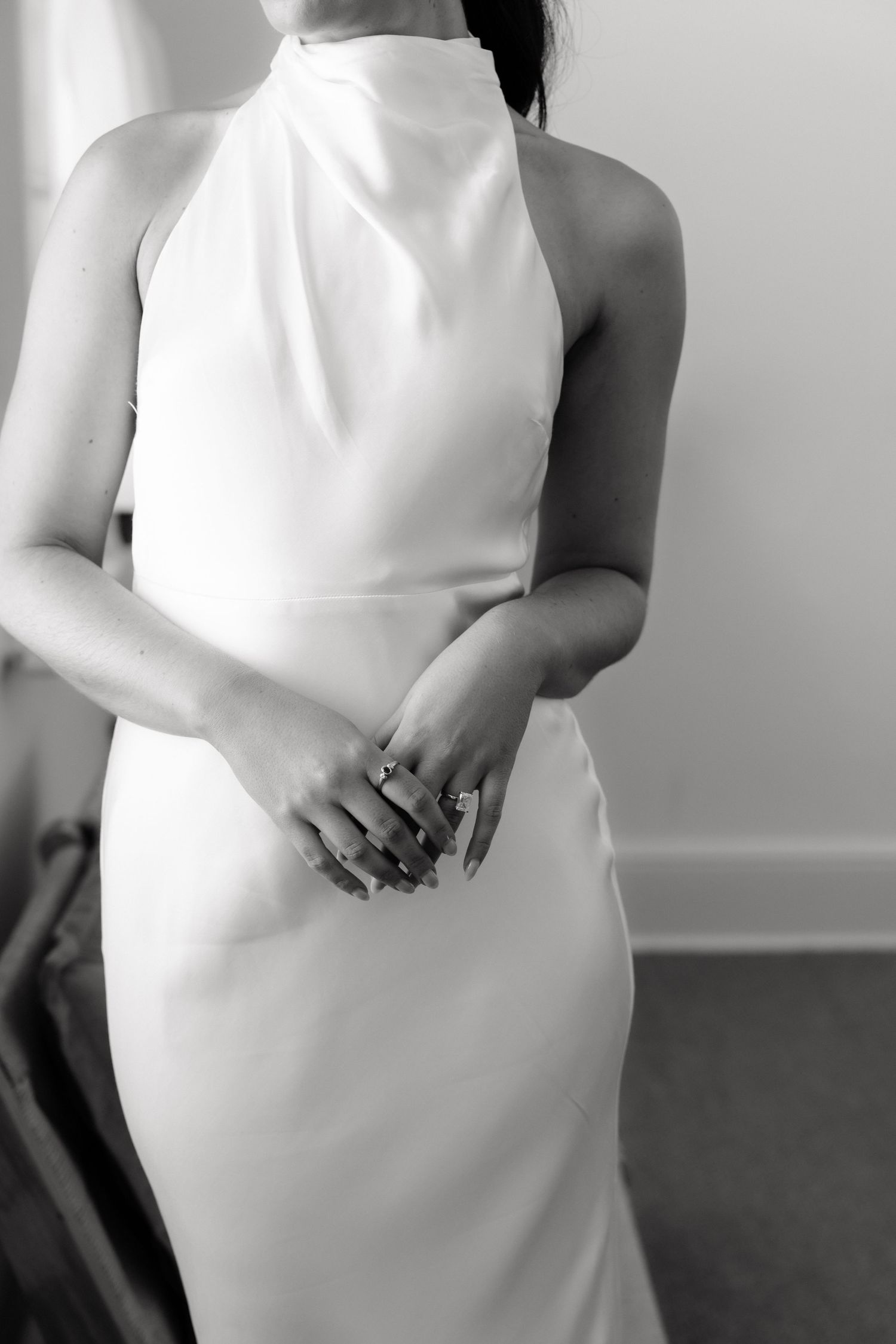Black and white close-up of bride in sleek halter neck wedding gown with ring.