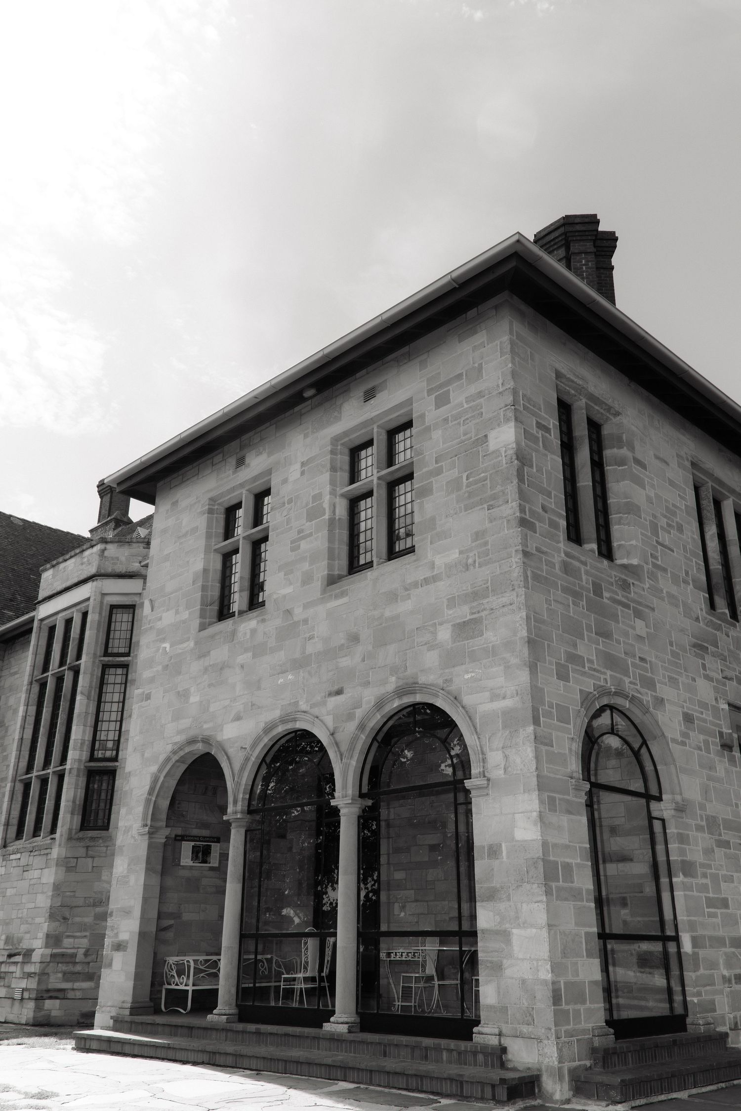 Black and white photo of a historic two-story stone building with arched windows and columns.