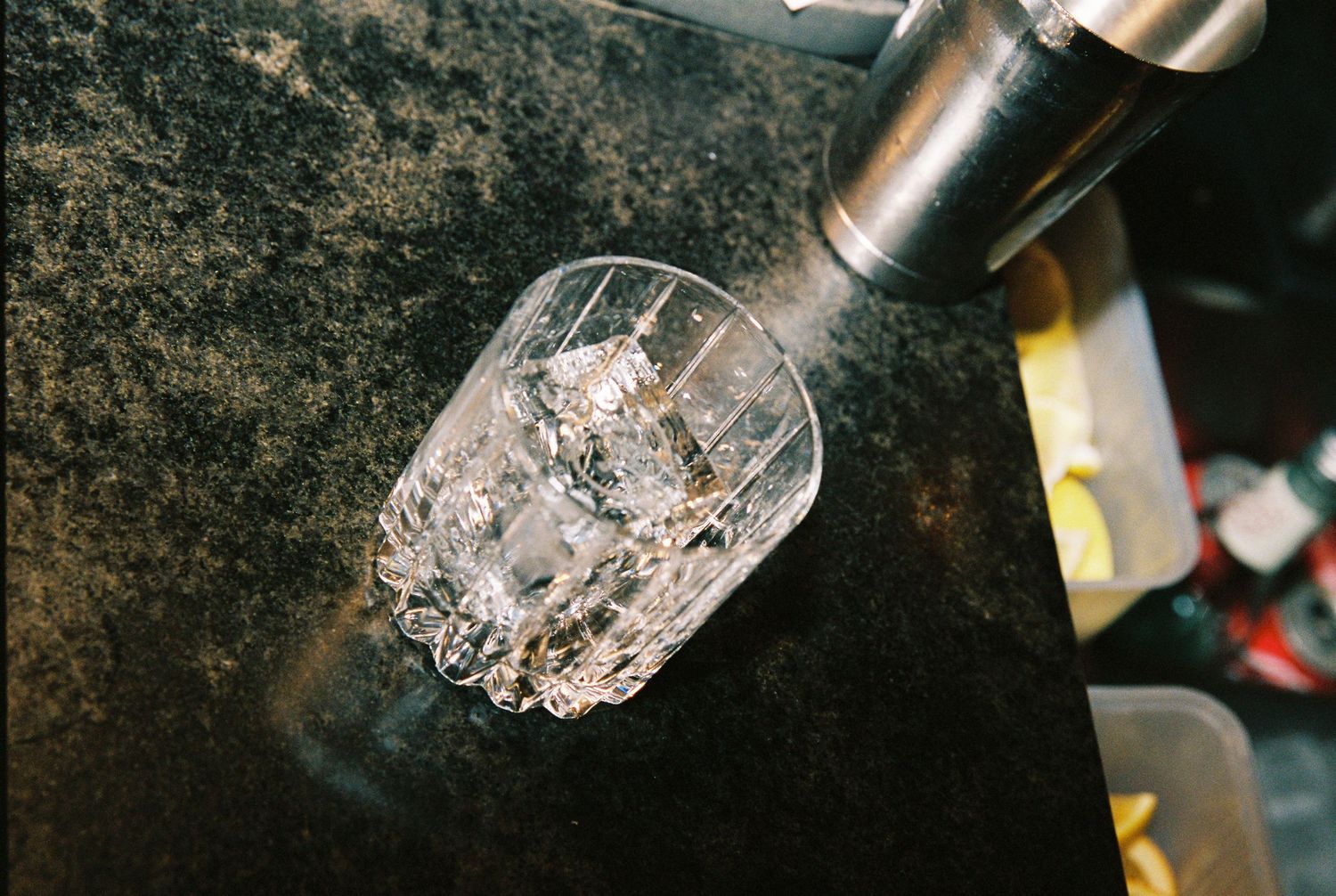 Crystal rocks glass filled with ice being poured at a wedding reception bar.