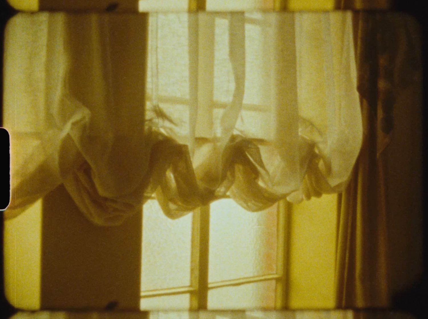 Sheer white curtains gathered and tied, glowing with warm golden light filtering through a vintage window.