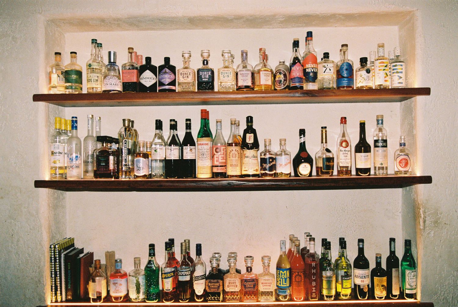 Wedding bar shelves lined with assortment of liquor bottles in stone alcove.