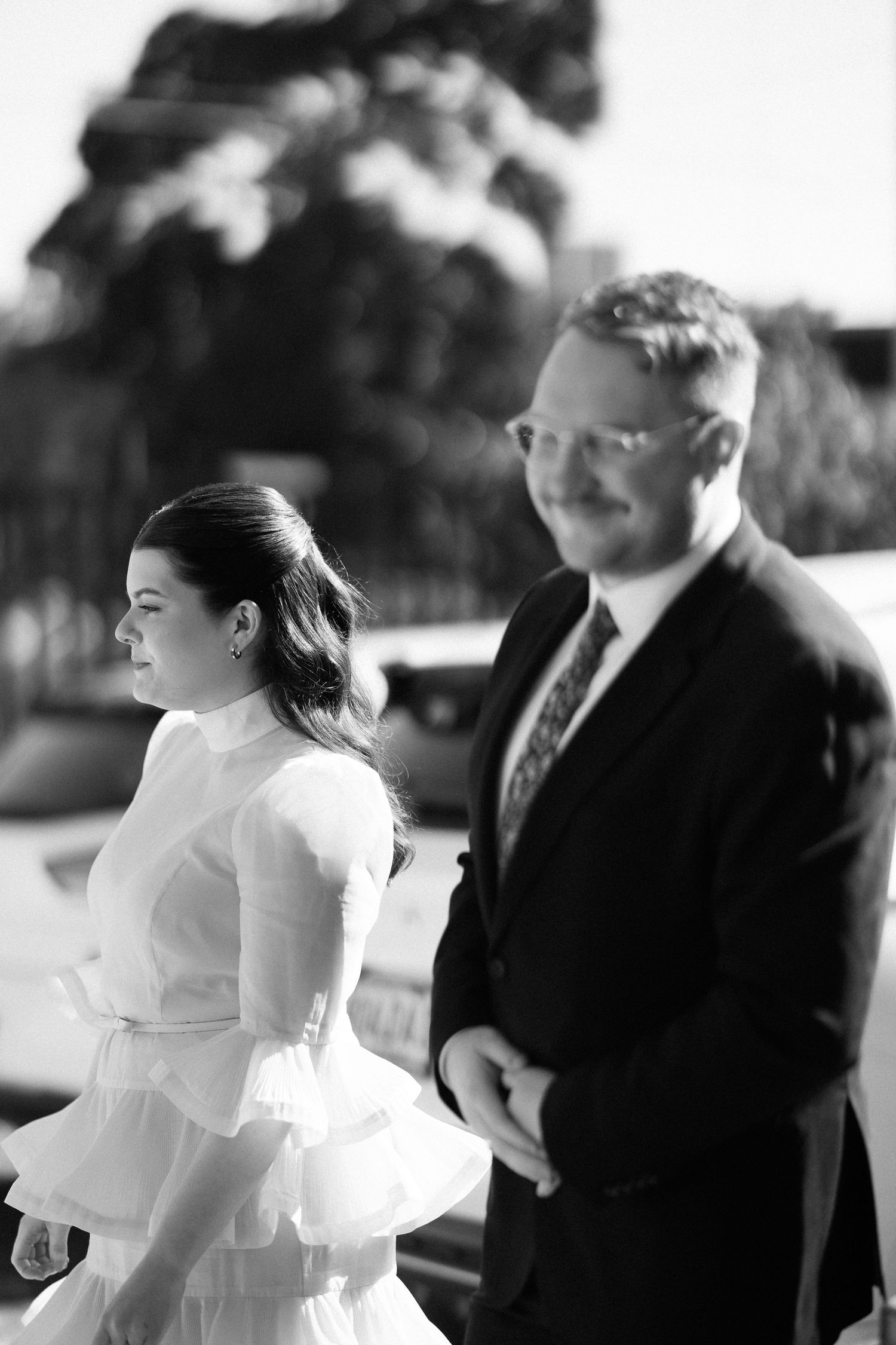 Black and white photo of bride and groom walking together outside after wedding ceremony.