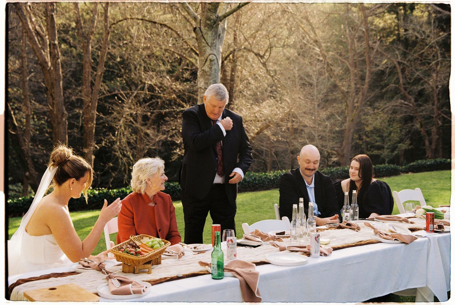 Wedding guests seated at elegant outdoor dining table during garden reception.