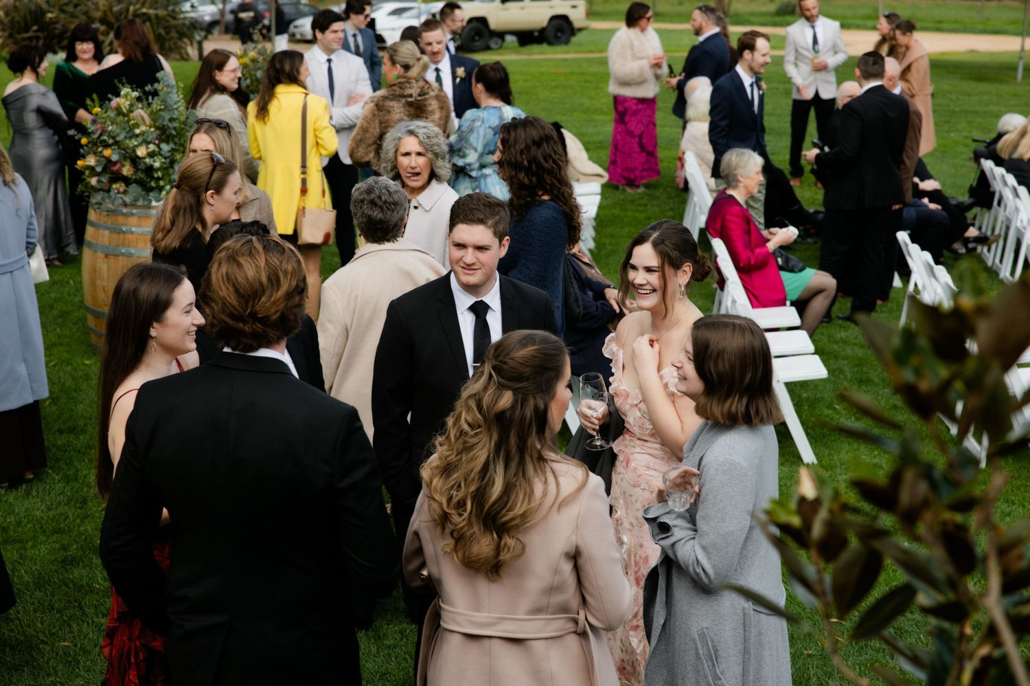 Guests mingling outdoors at an elegant wedding reception on a green lawn, dressed in formal attire.