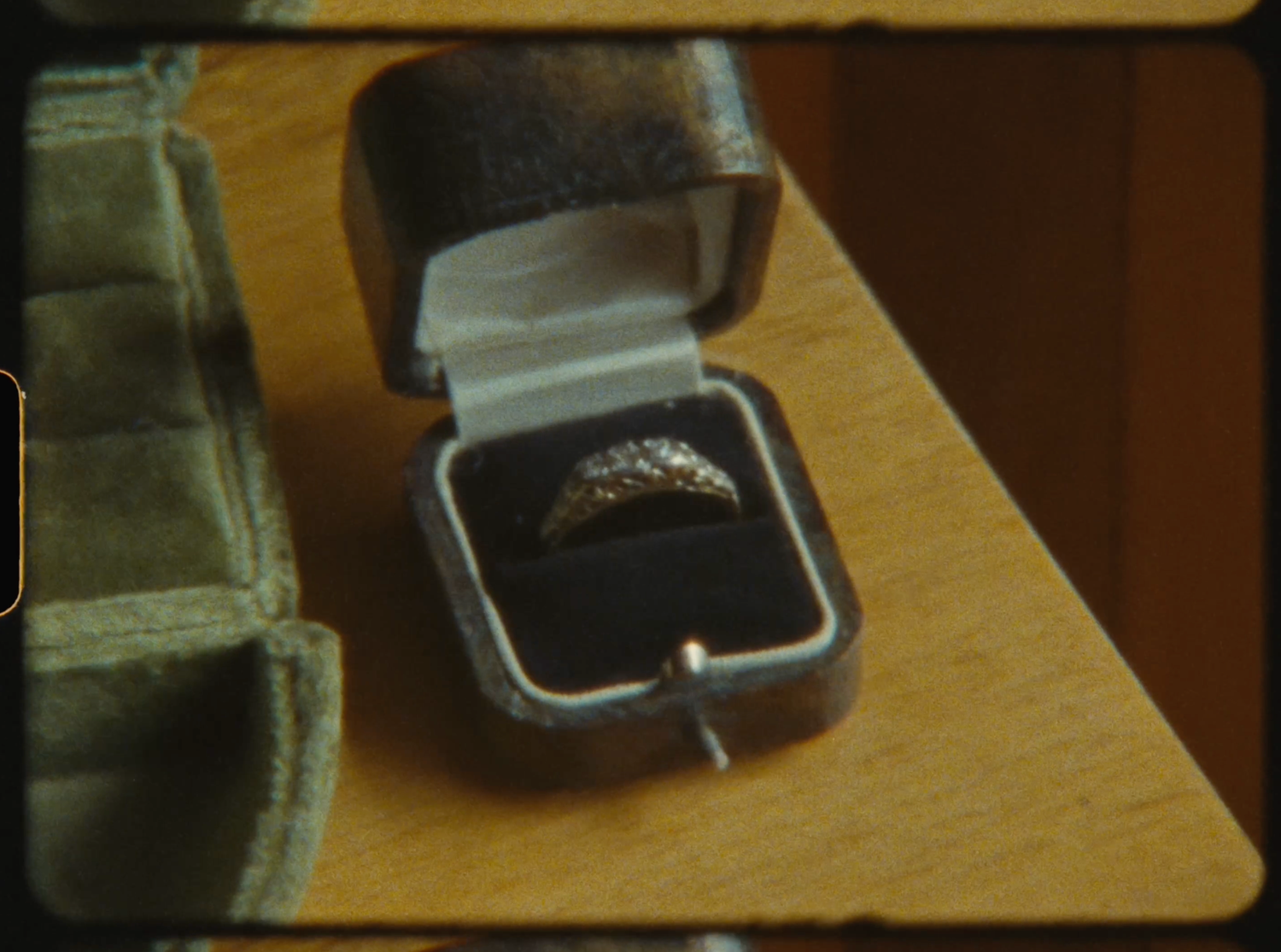 Diamond ring displayed in a gray velvet jewelry box on a wooden surface.