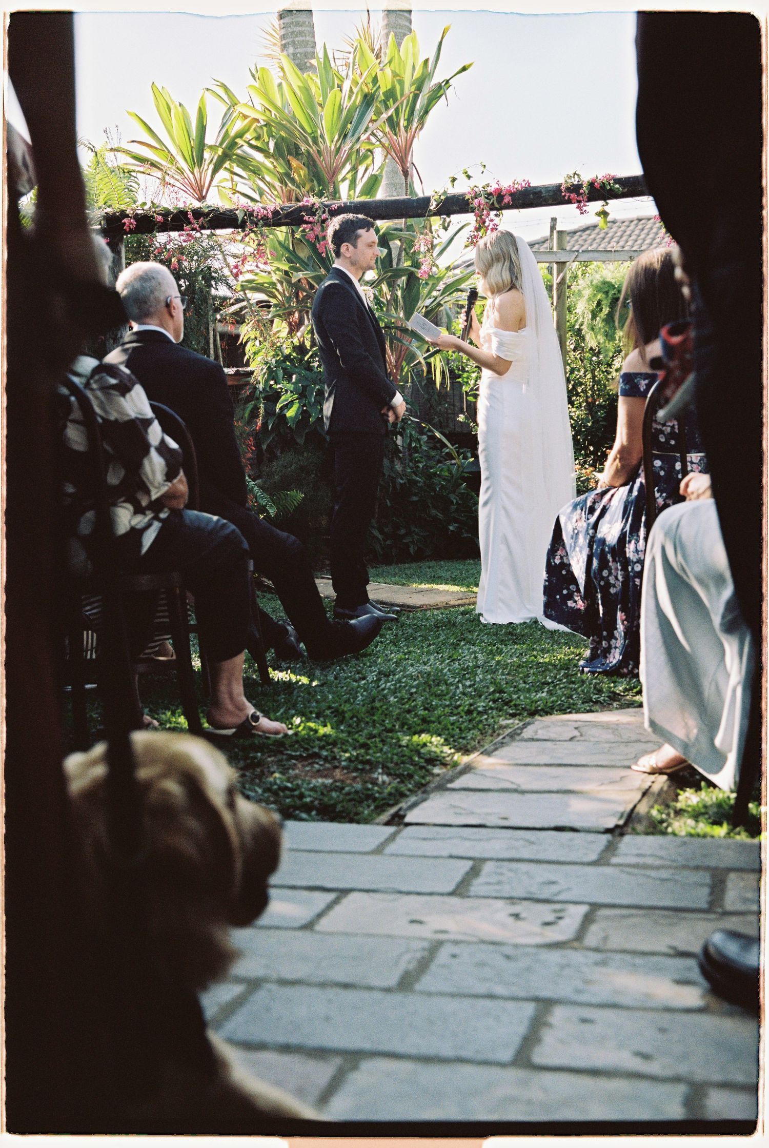 Bride and groom exchange vows under floral arch at intimate garden wedding ceremony.