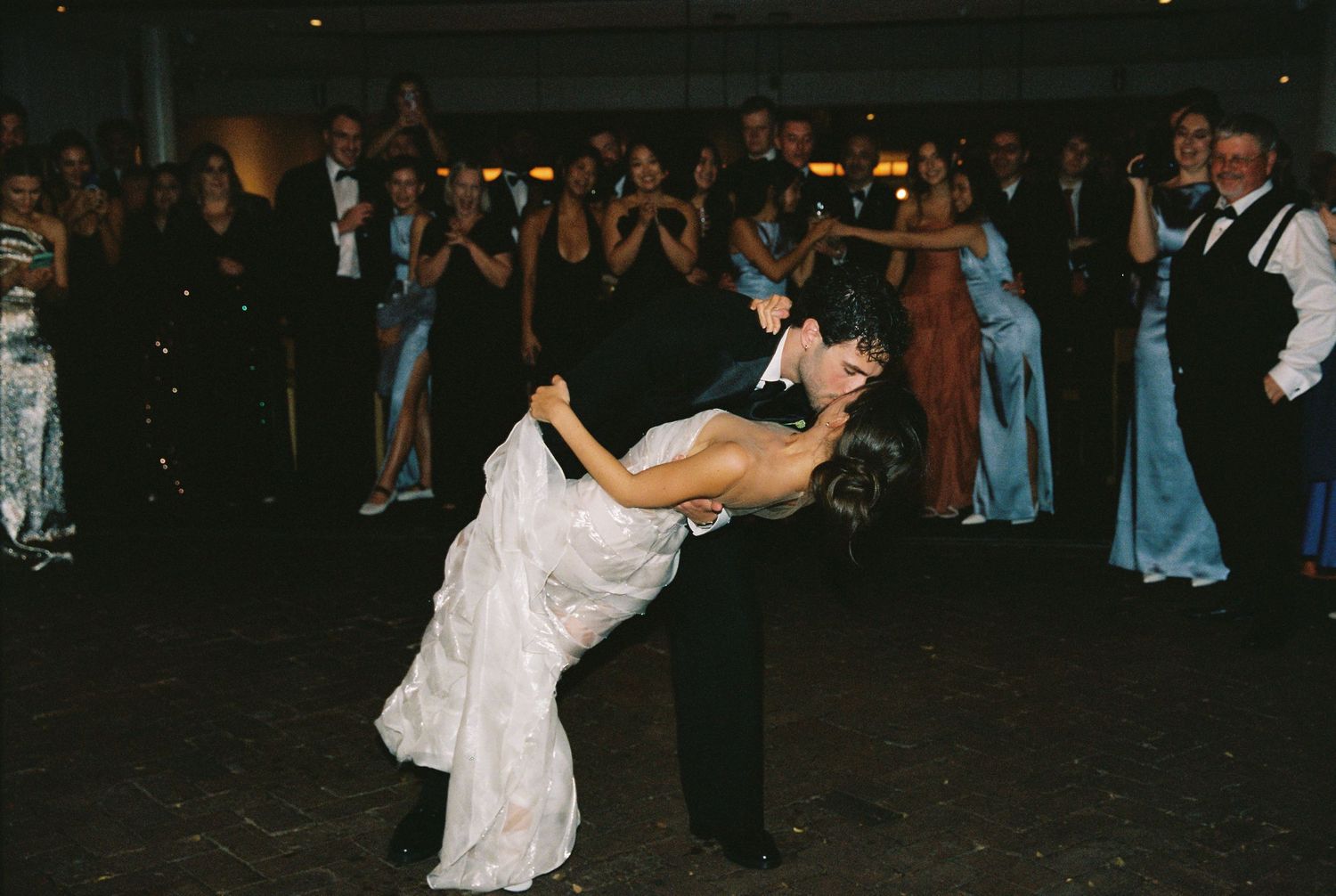 Groom dips bride in wedding dress during first dance at reception.