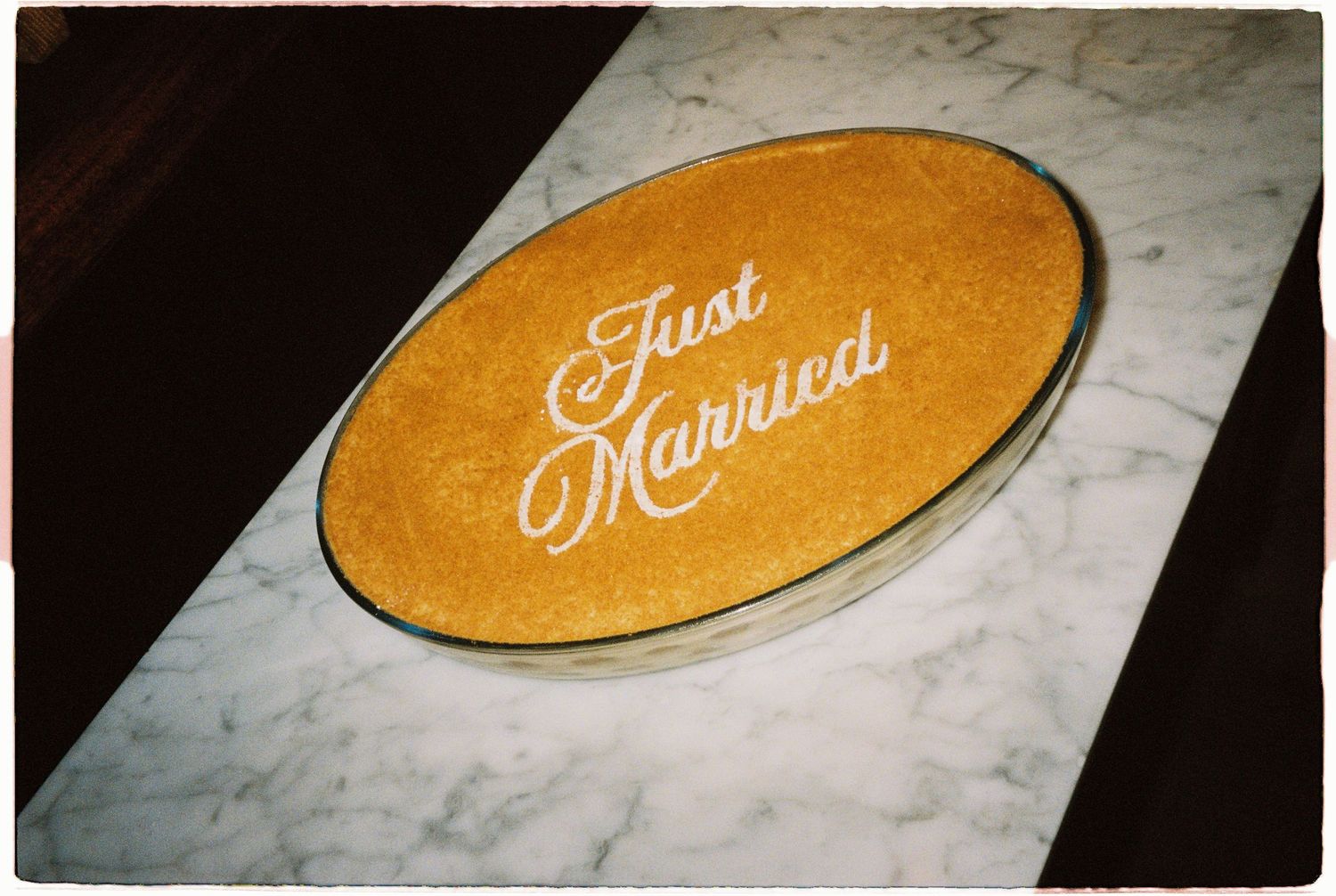 Elegant oval Just Married sign with gold glitter lettering displayed on a marble surface.