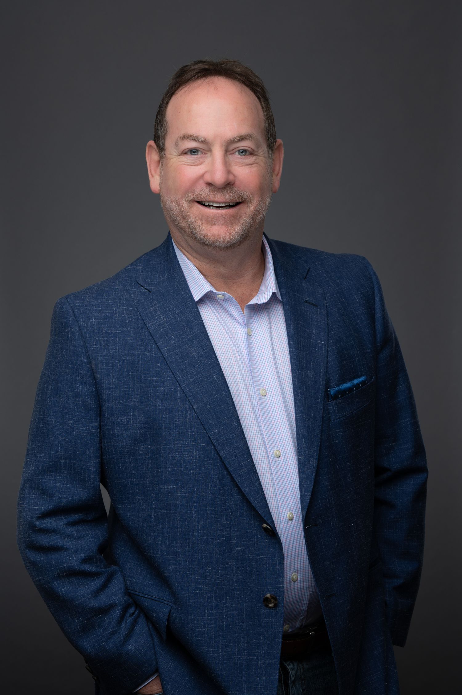 Smiling man in a blue blazer posing confidently for a professional business headshot.