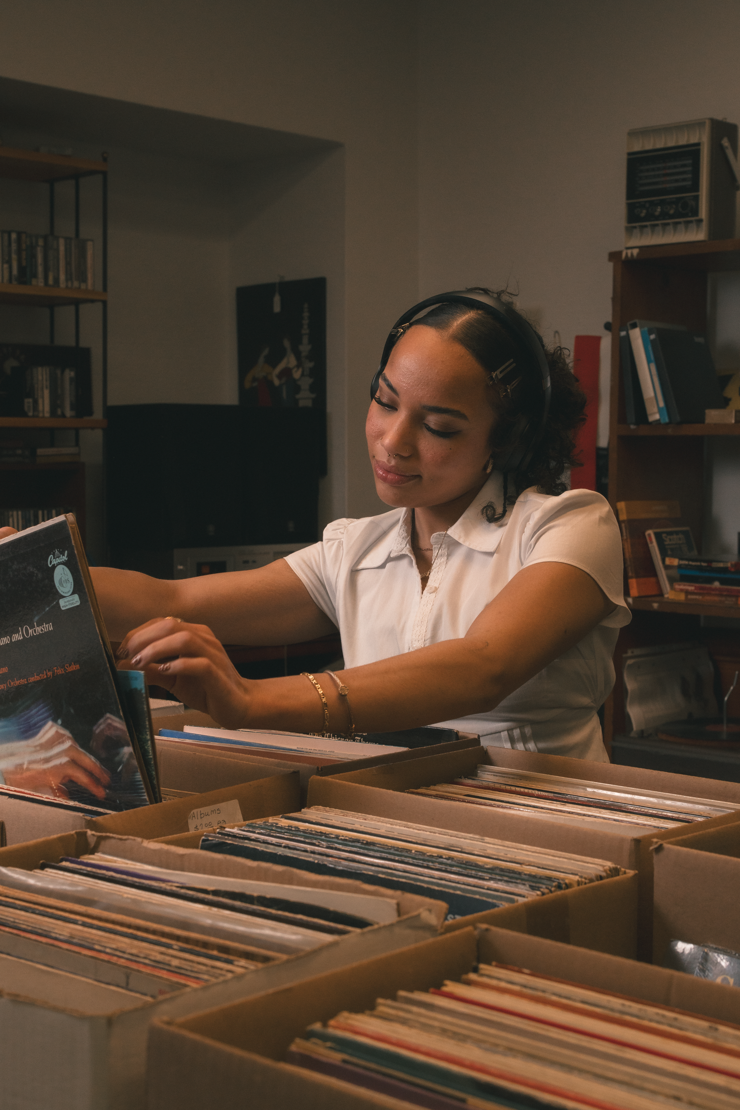 Young woman flipping through vinyl records in boxes at a vintage record store.
