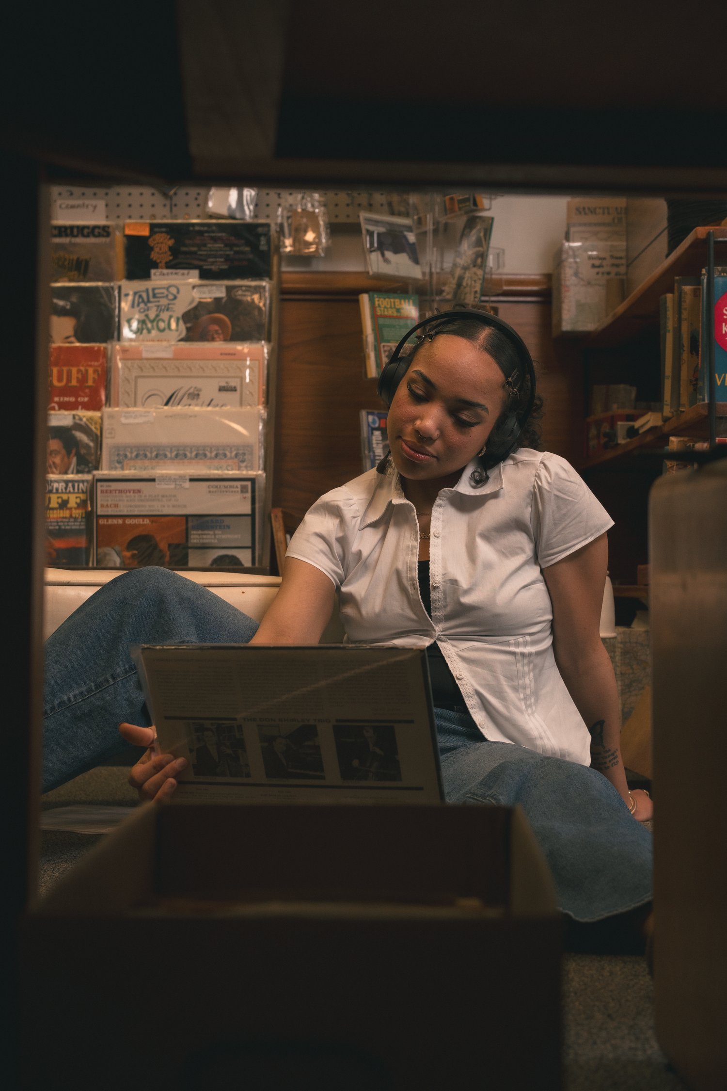 Young woman browsing vinyl records while sitting on floor of a record store.