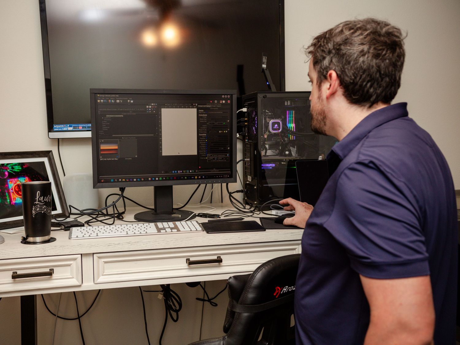 Photographer editing images on a large monitor at a professional desktop workstation setup.